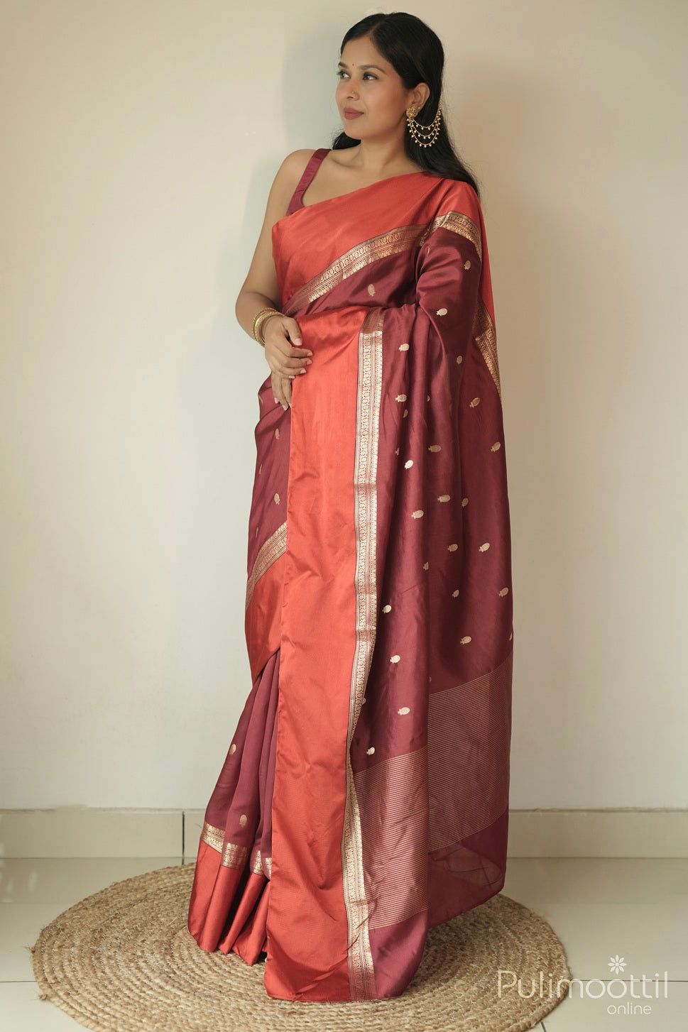 Woman wearing maroon mango silk saree with golden buttas and satin border, styled for traditional festive wear.