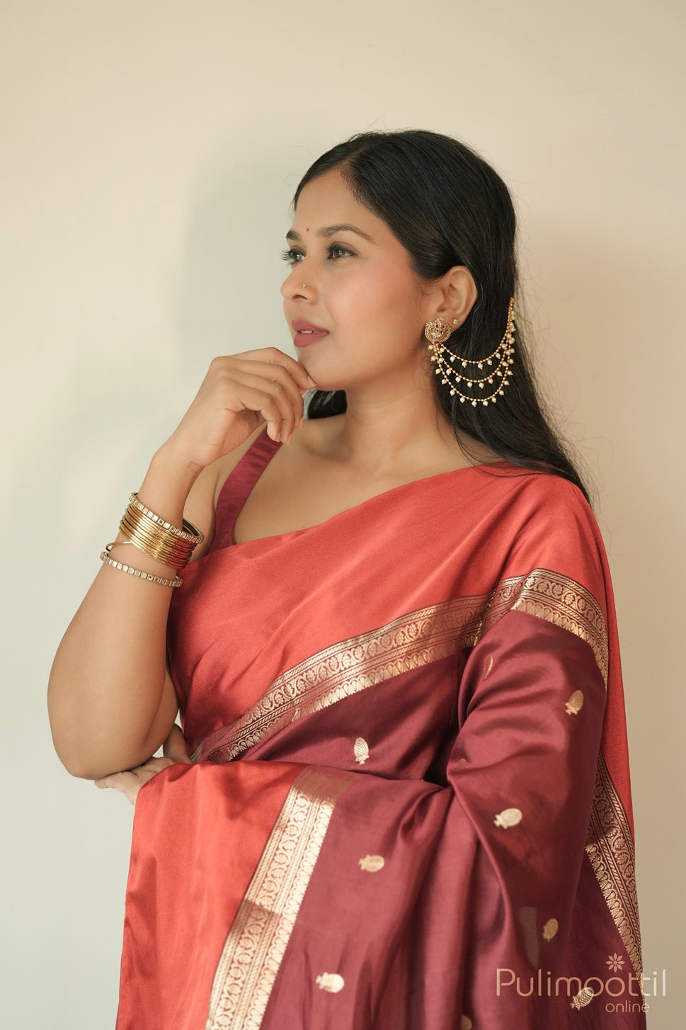 Model draped in maroon silk saree featuring golden buttas and rich satin border, ideal for women’s weddings and celebrations.