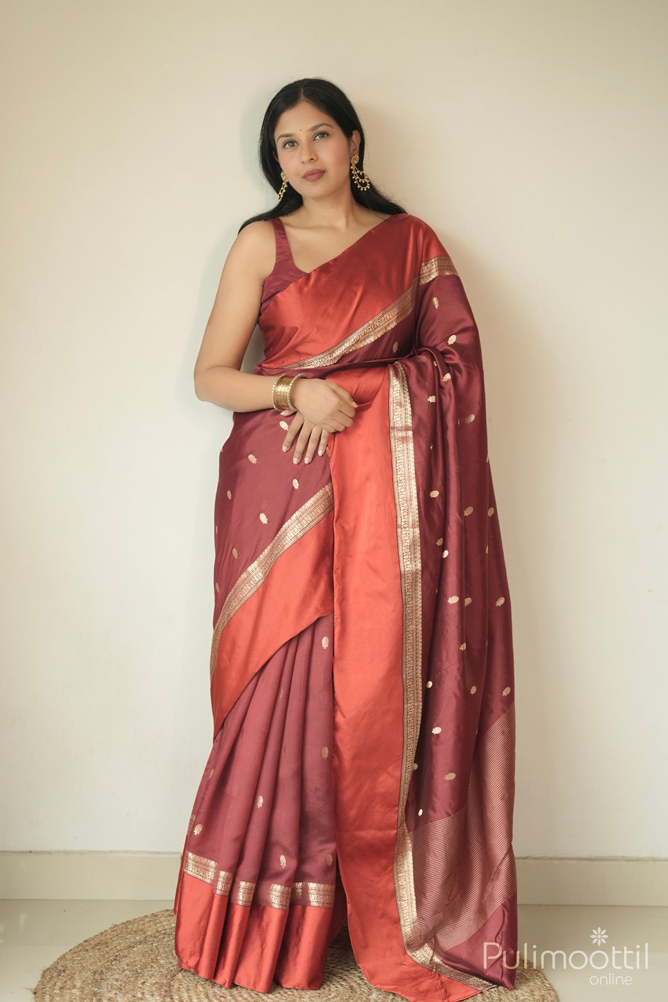 Elegant maroon mango silk saree with golden motifs and satin border, showcased by a woman for festive fashion.