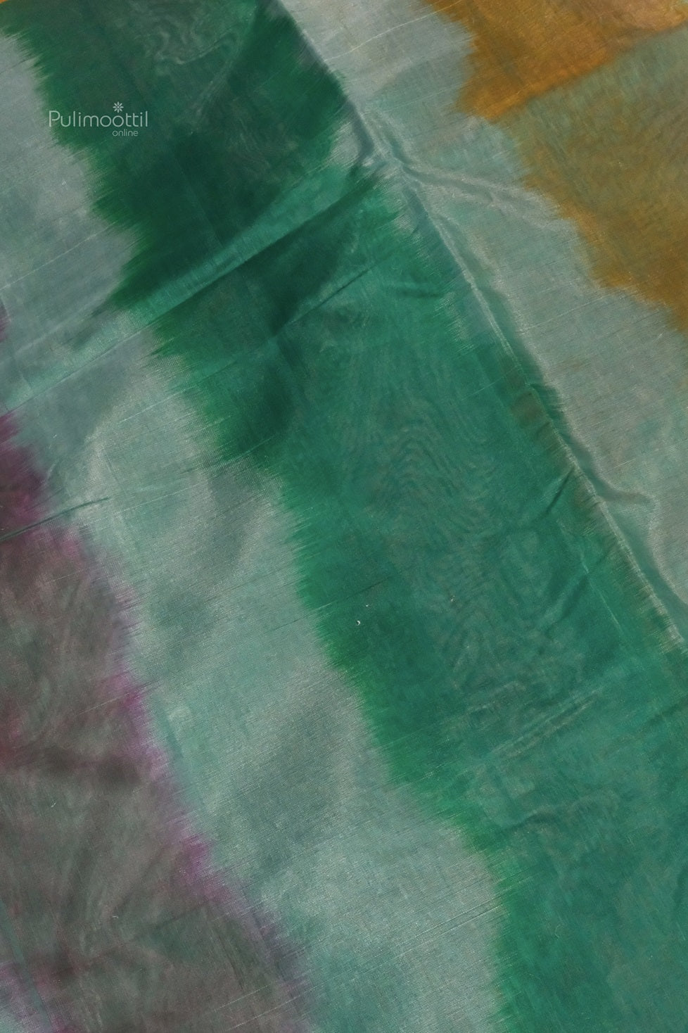 An artistic close-up of the pallu, showing broad strokes of green, violet, and mustard in a watercolor effect on a shimmering grey base.