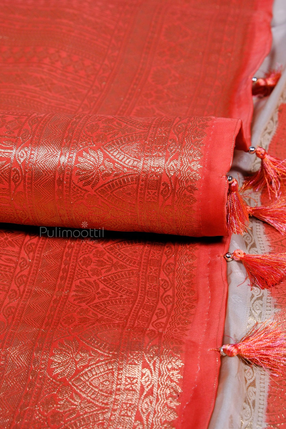 Tassel edge of pure organza Banarasi saree with red pallu and golden zari detailing.