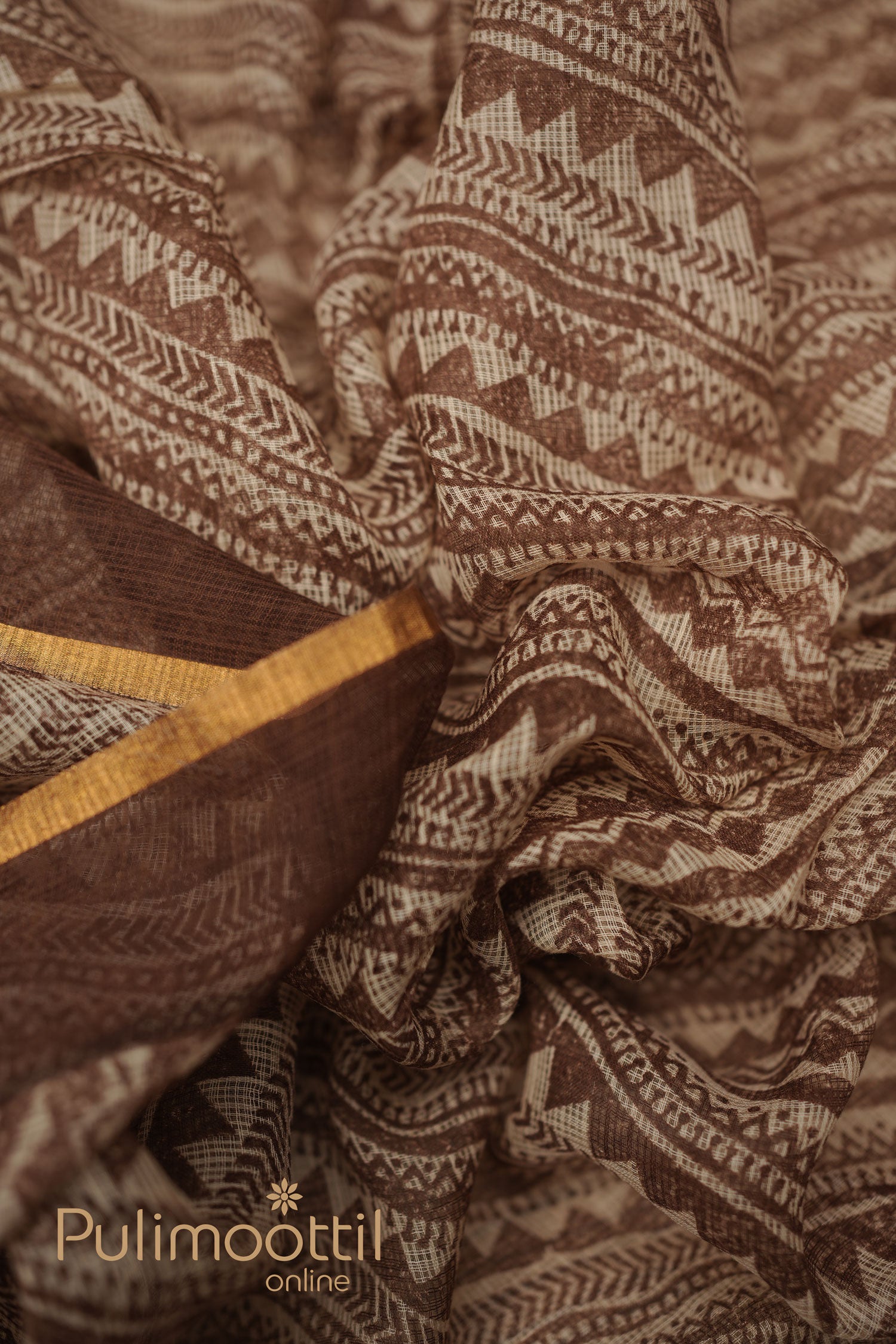 Close-up of multi-shaded soft net-cotton saree with geometric patterns of zigzags and lines, accented by a golden border.