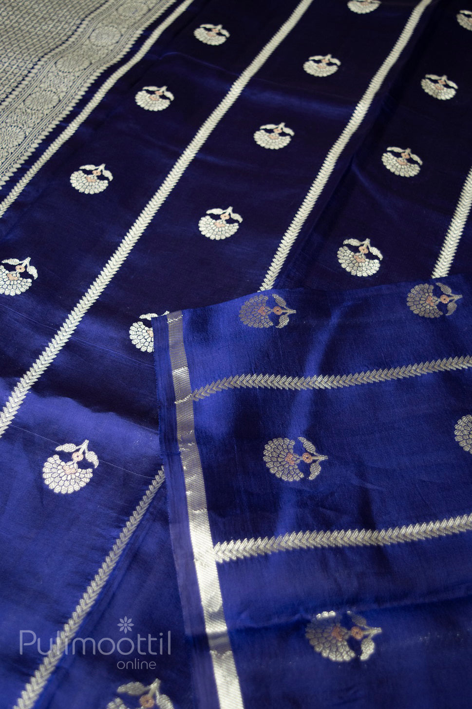 Flat layout of navy blue Banarasi silk saree with silver and gold zari floral motifs, vertical stripe patterns, and elegant brocade-style pallu border.

