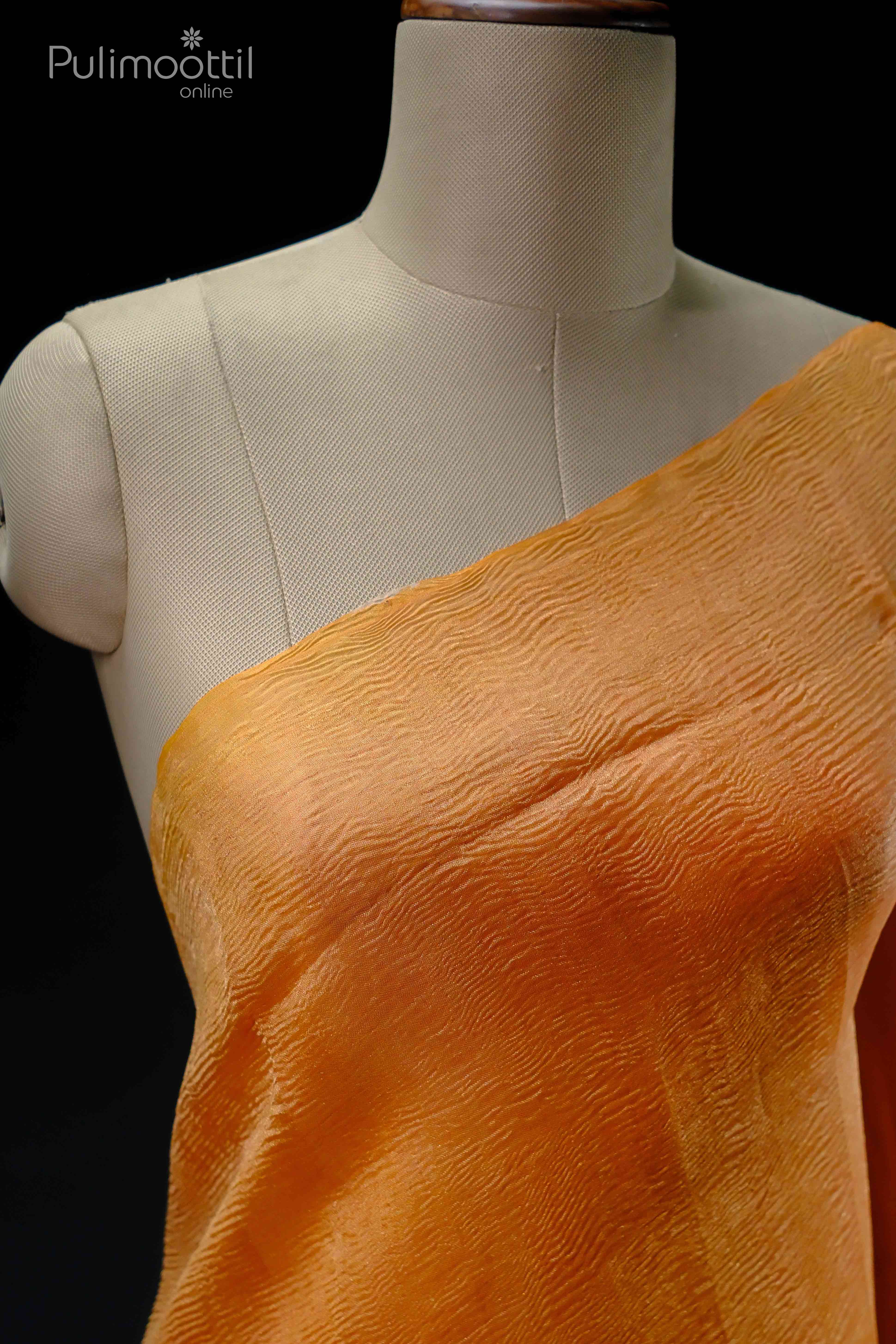 Neon orange crushed tissue saree draped on a mannequin, showcasing its texture and color, plain without a border.