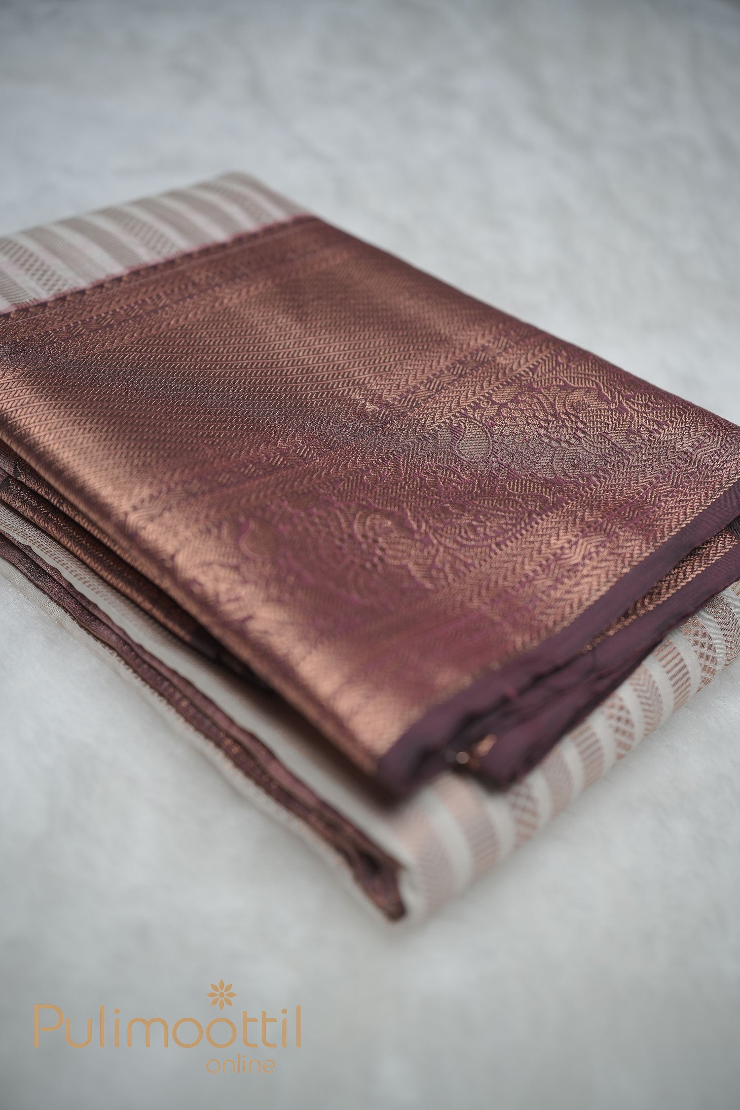 alt="Bronze-gold Kanchipuram saree with jacquard floral zari pattern on striped cream-gold base"
