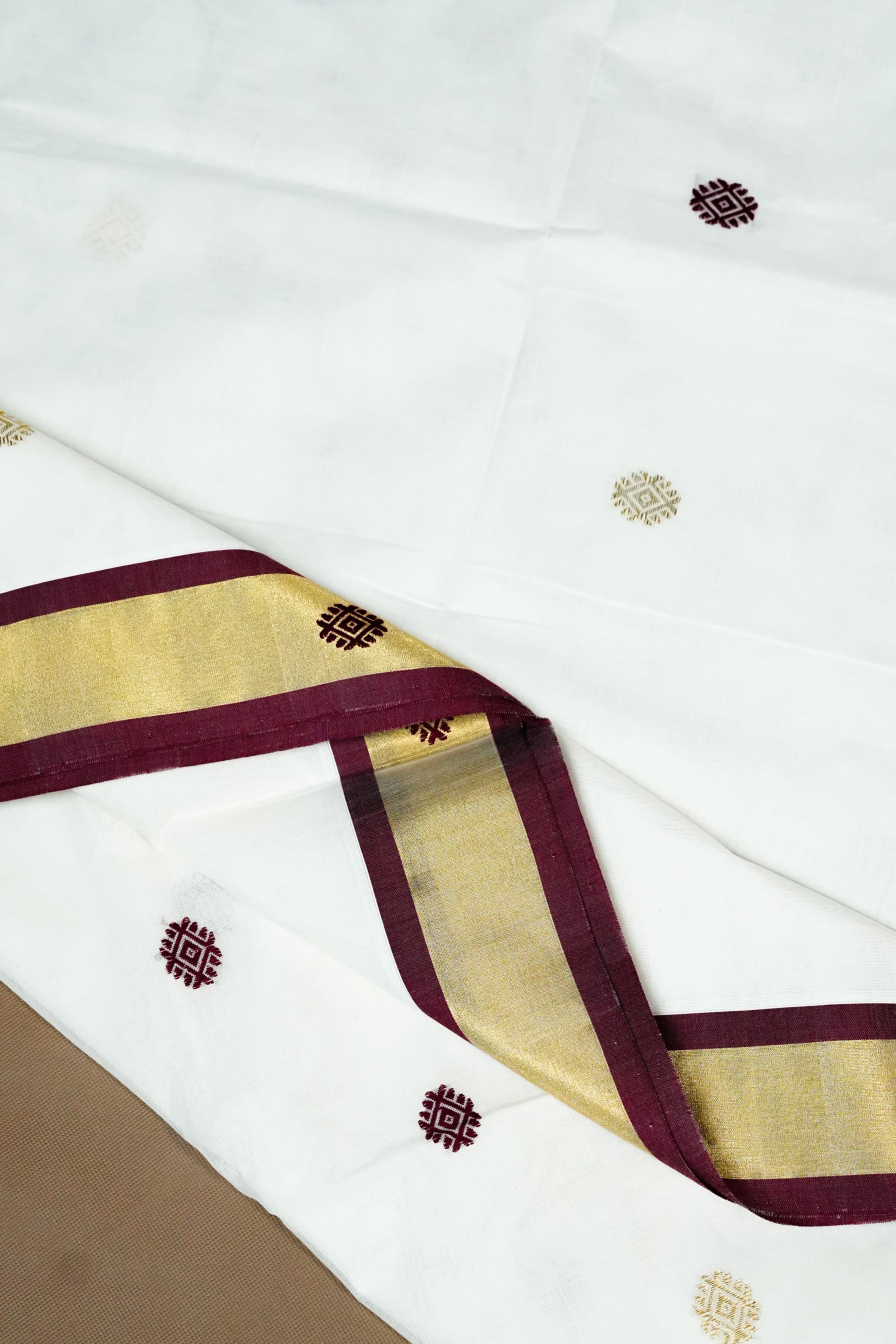 Off White Kerala Set Saree with maroon and golden tissue border, adorned with mixed zari motifs in gold and maroon.