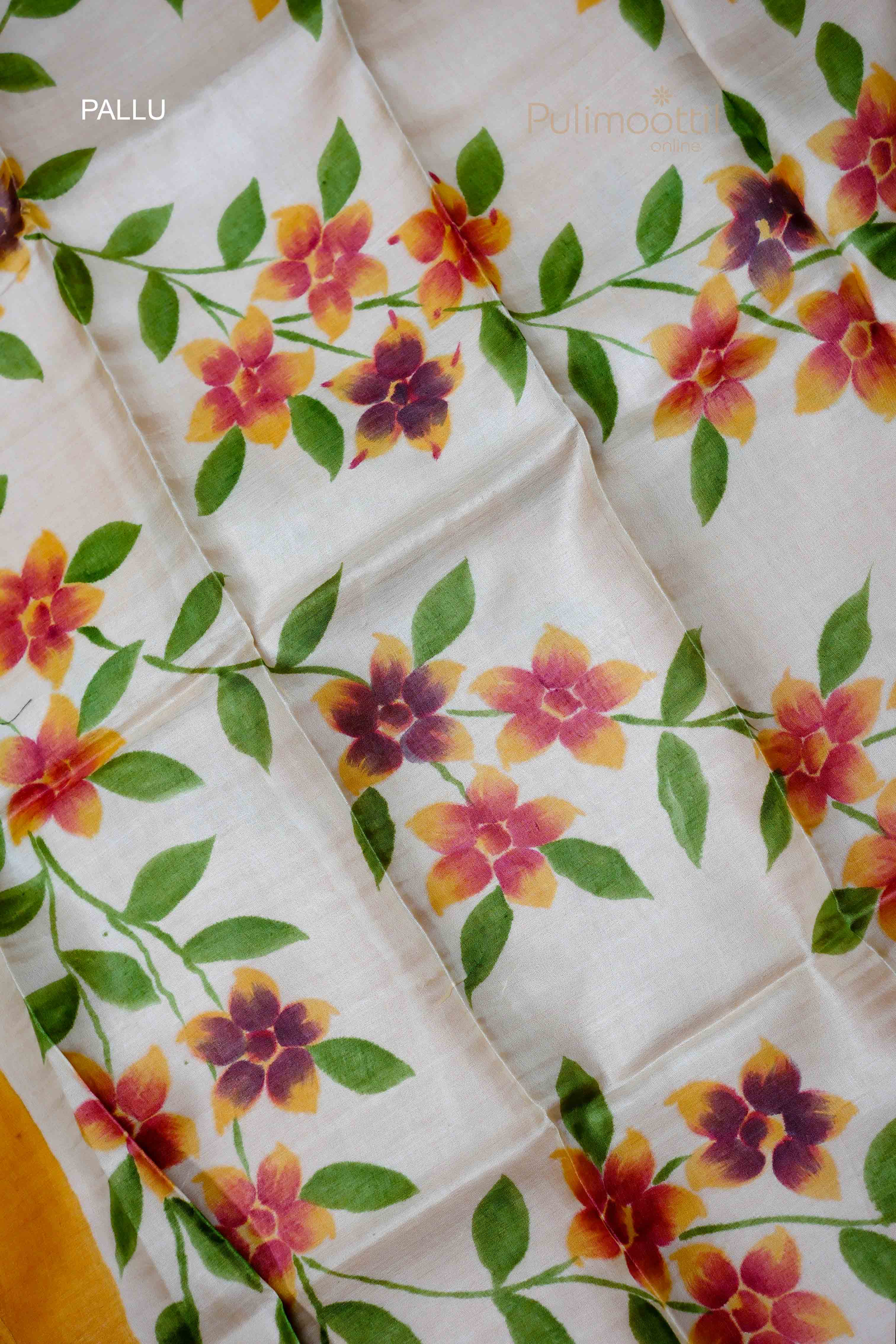 Detailed view of the pallu of the saree, featuring a floral design in shades of orange, pink, and green.