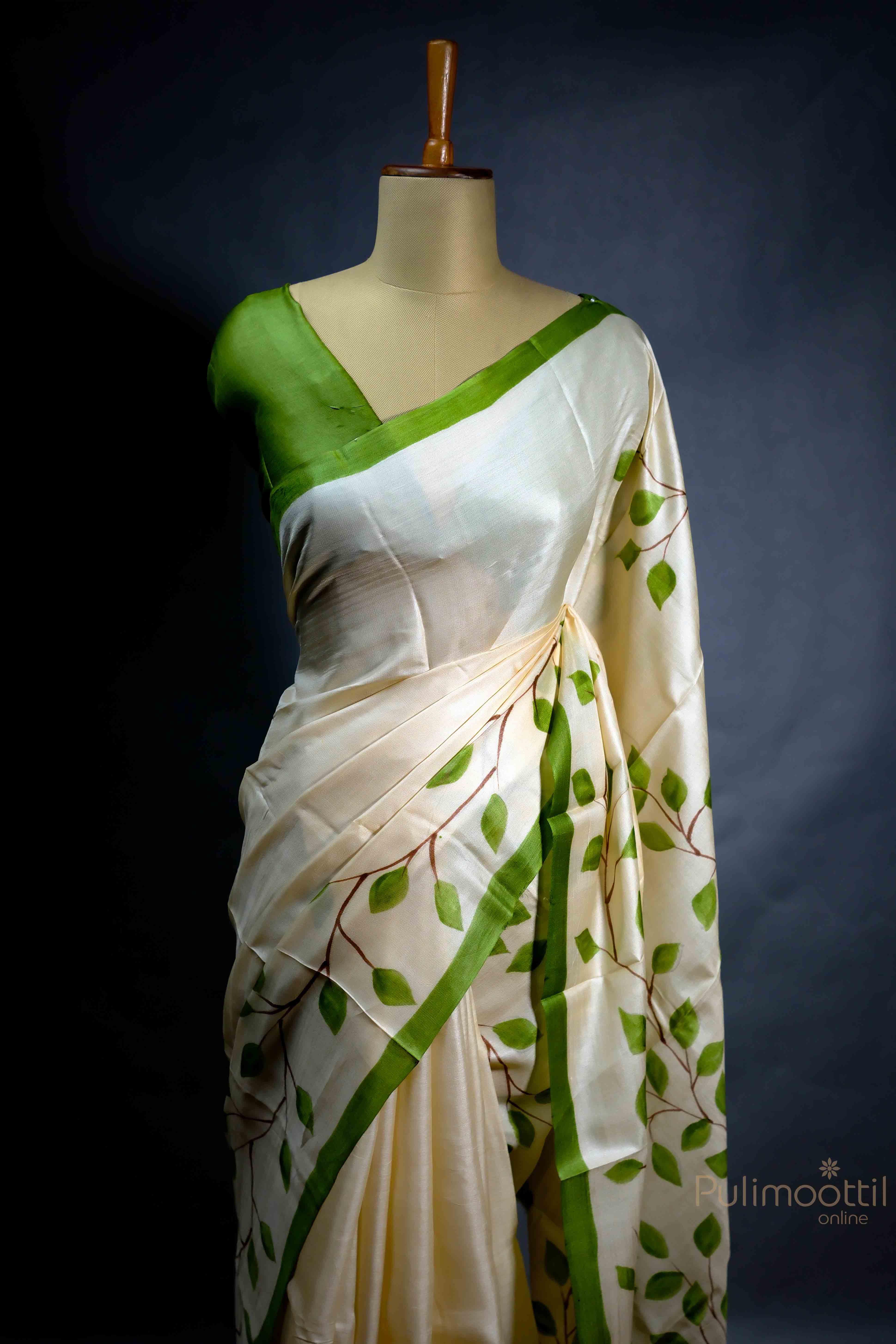 Off-white pure printed Tassar Onam saree with floral design and green contrast border, draped elegantly on a mannequin.