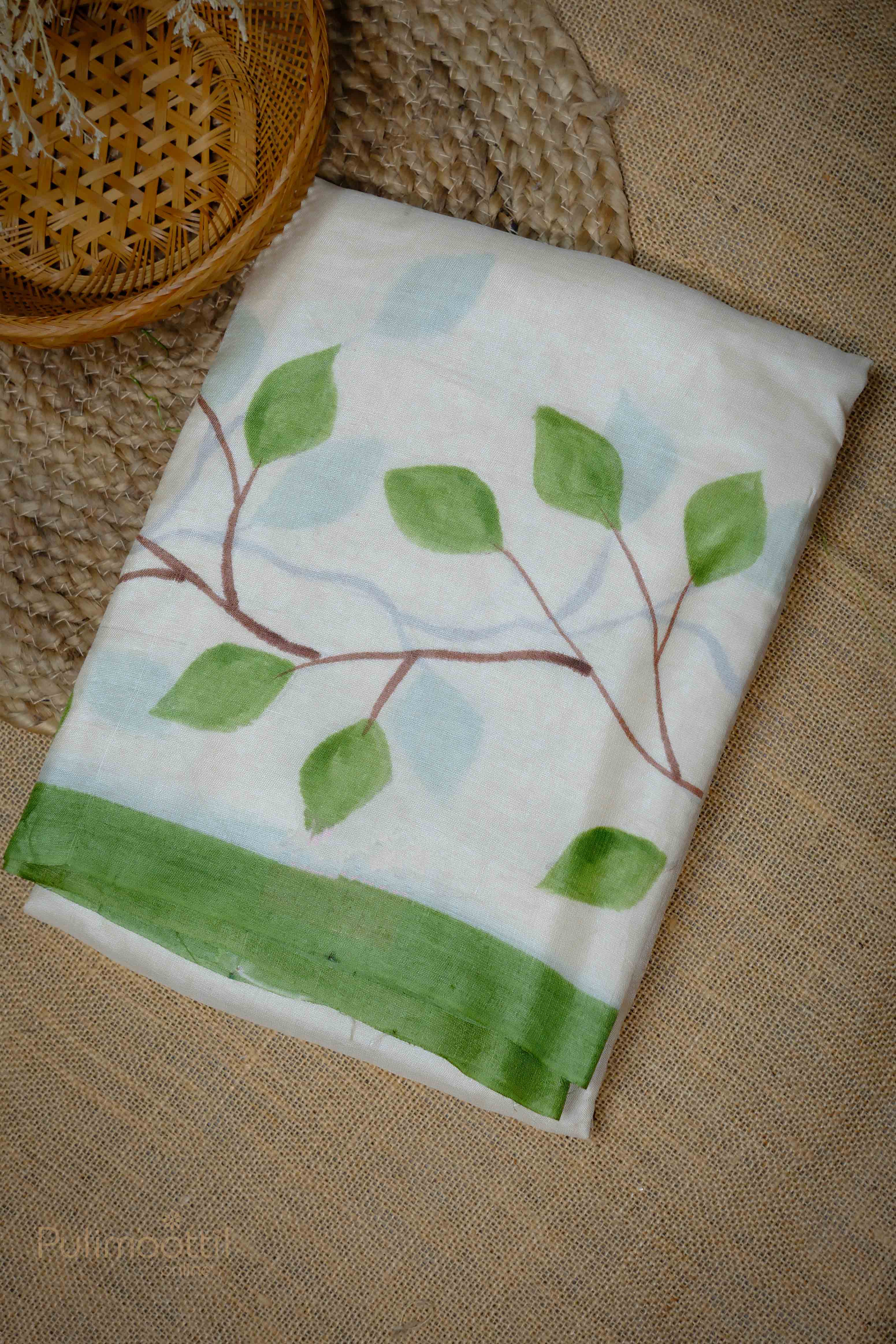 Folded off-white Tassar Onam saree showcasing the floral print and green contrast border at the edge.