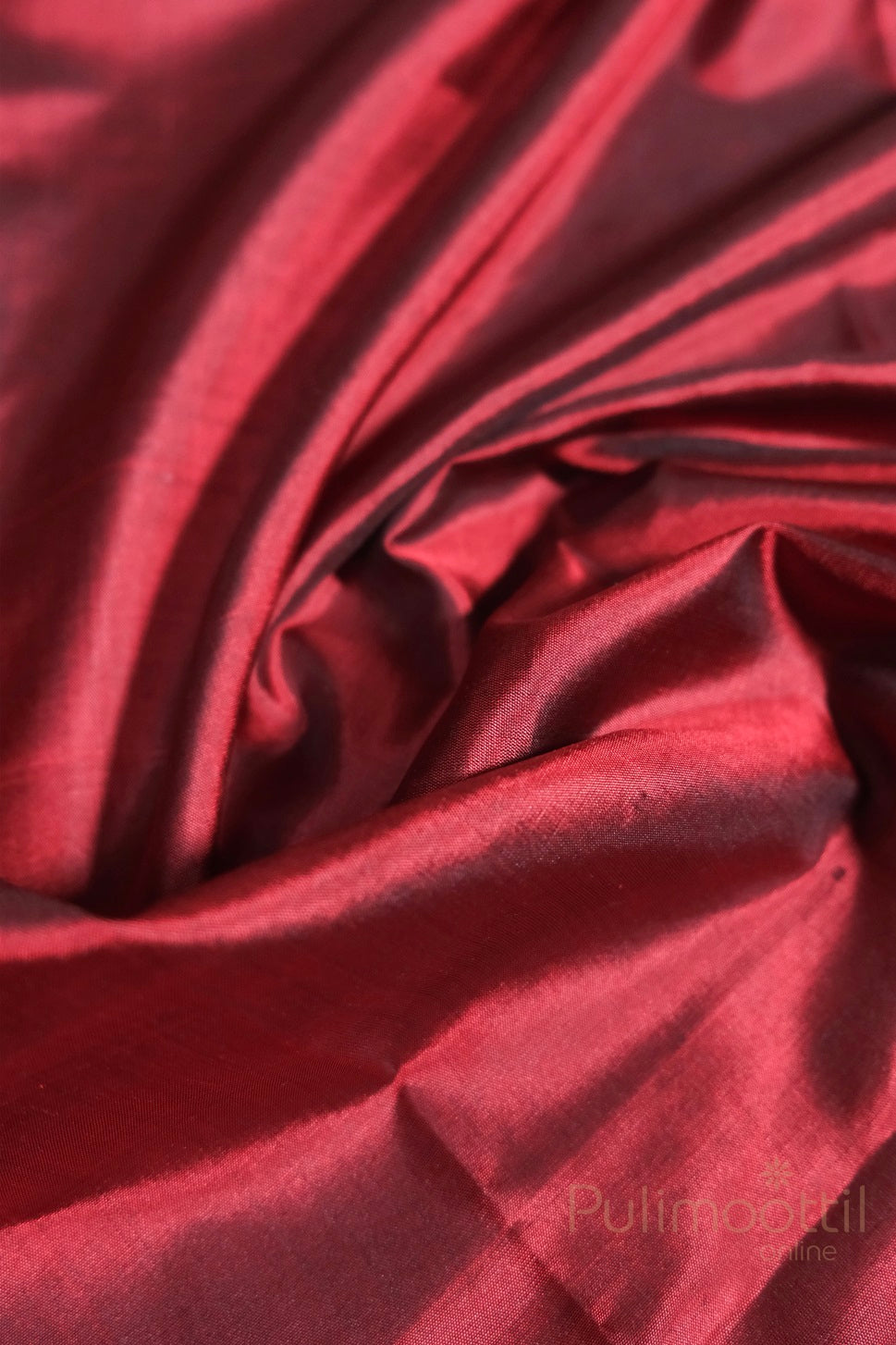 Close-up of rich maroon soft silk fabric showcasing its smooth texture and subtle shine.