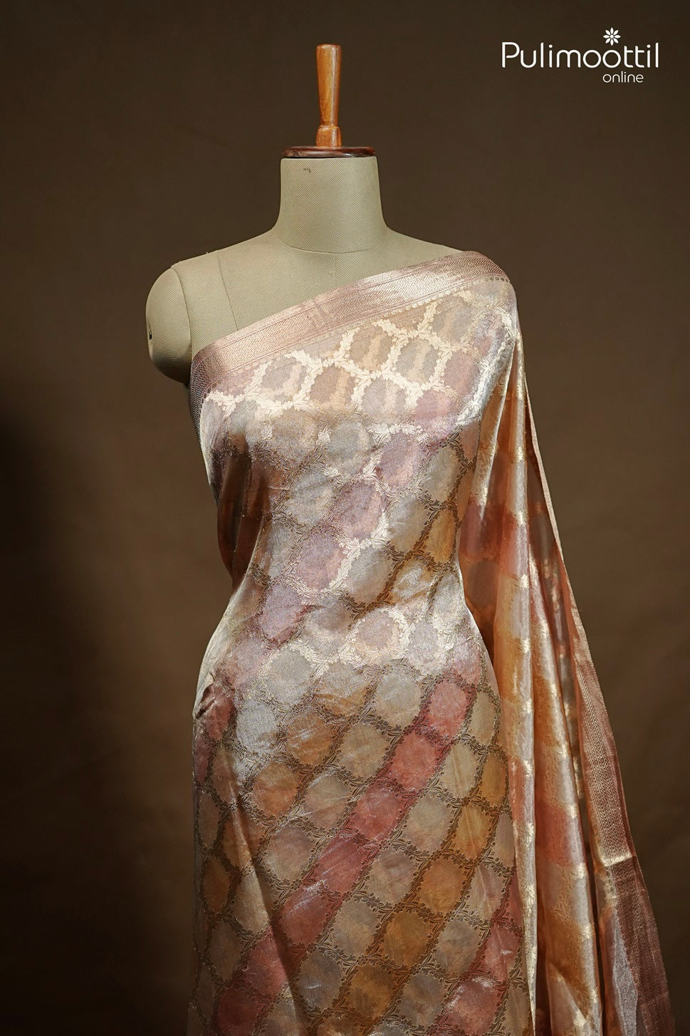 Pastel shading organza silk saree with golden zari work and zig zag zari border displayed on mannequin – Pulimoottil Online.