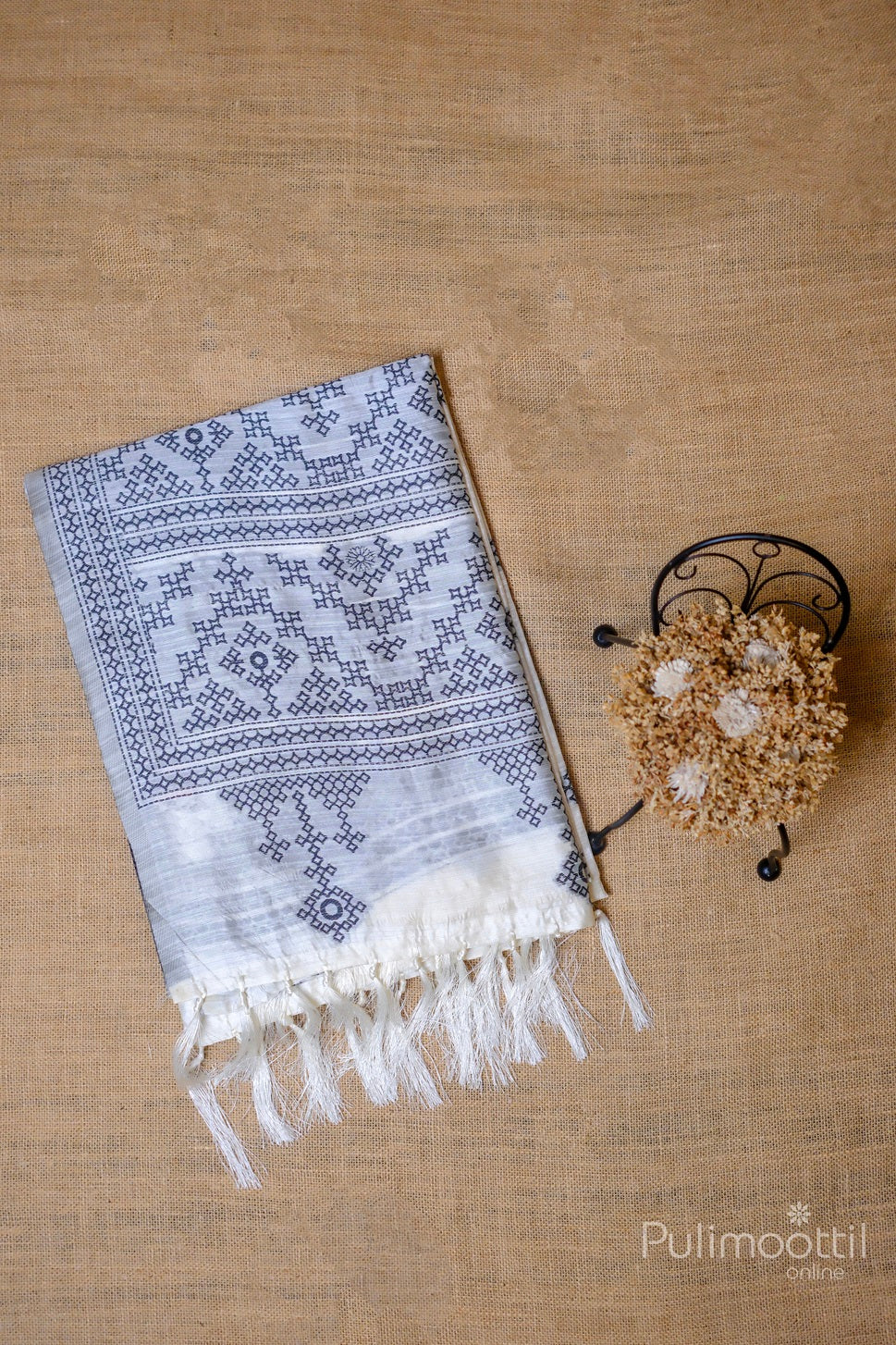 Close-up view of the off-white semi jute silk saree with delicate black Kutch work buttas, showing fine details of the fabric and embroidery.
