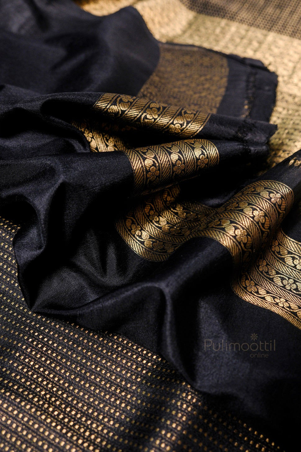 Close-up detail of golden silk fabric with ornate paisley and floral motifs in traditional Indian brocade weaving