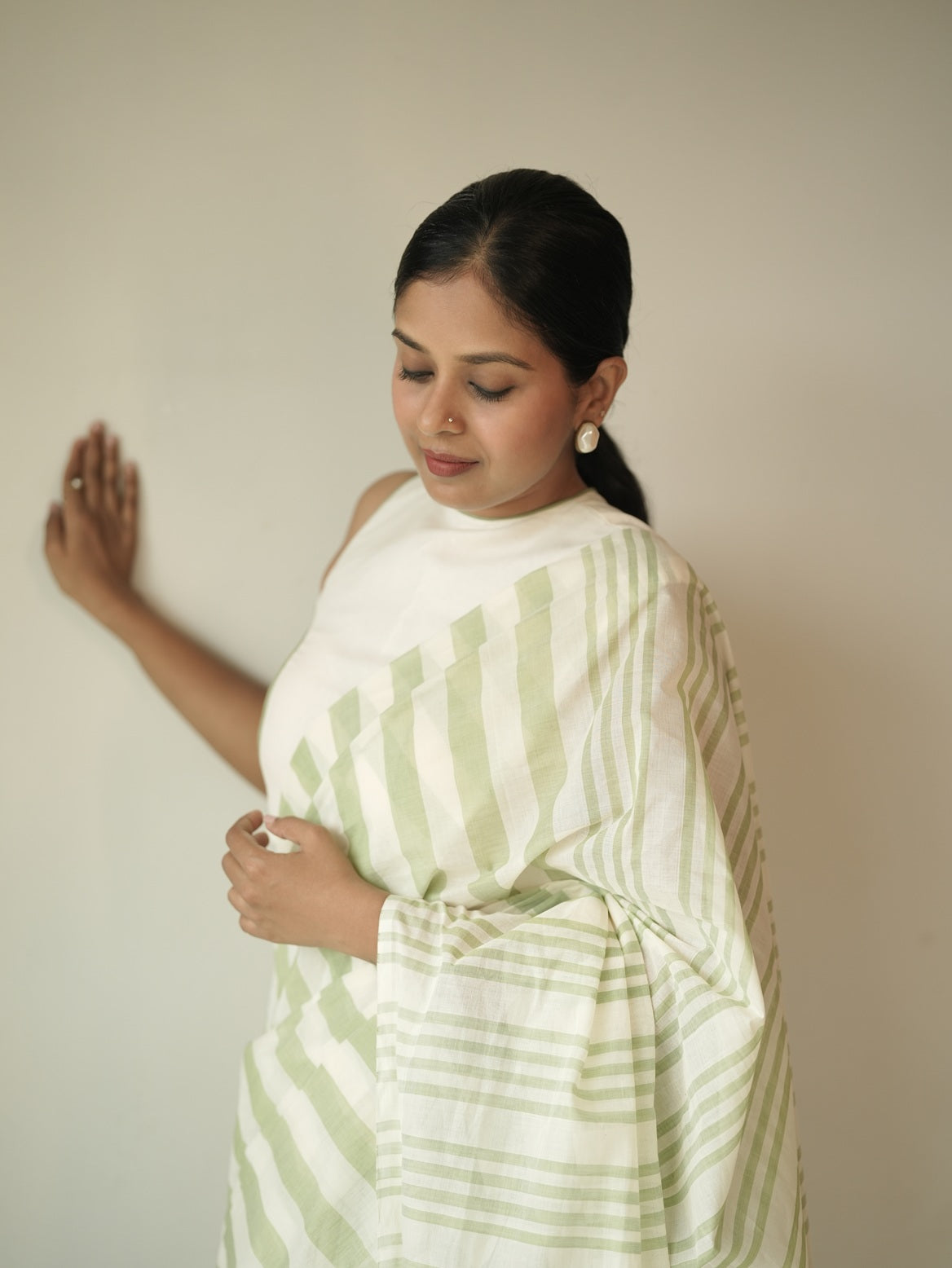 Close-up of pure handloom cotton saree in pastel green and cream stripes, borderless drape on model – sarees under 5000.