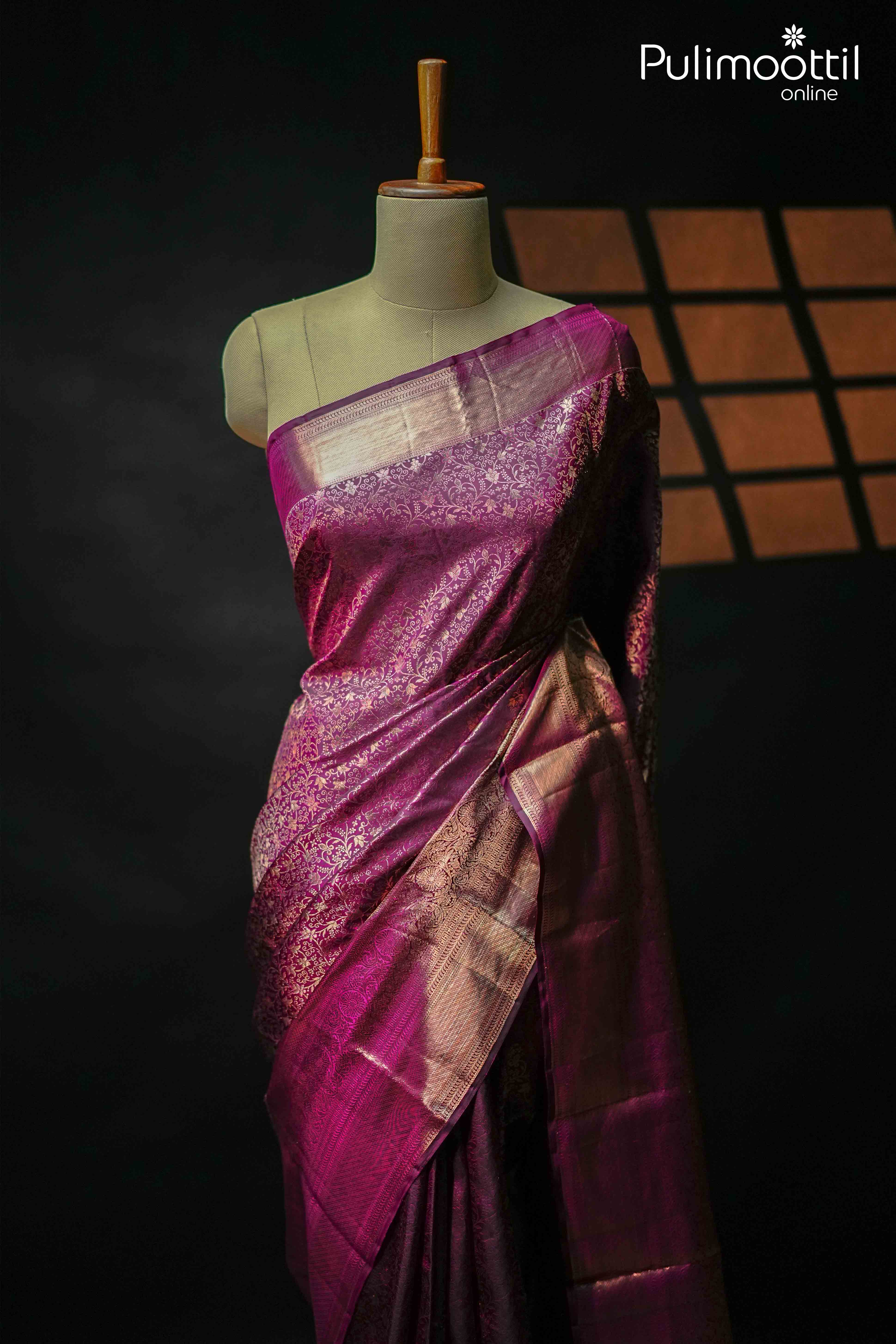 Elegant purple plum Kanchipuram silk saree draped on a mannequin, featuring rich copper zari floral motifs with a one-sided heavy floral creeper border, perfect for weddings and festive occasions.
