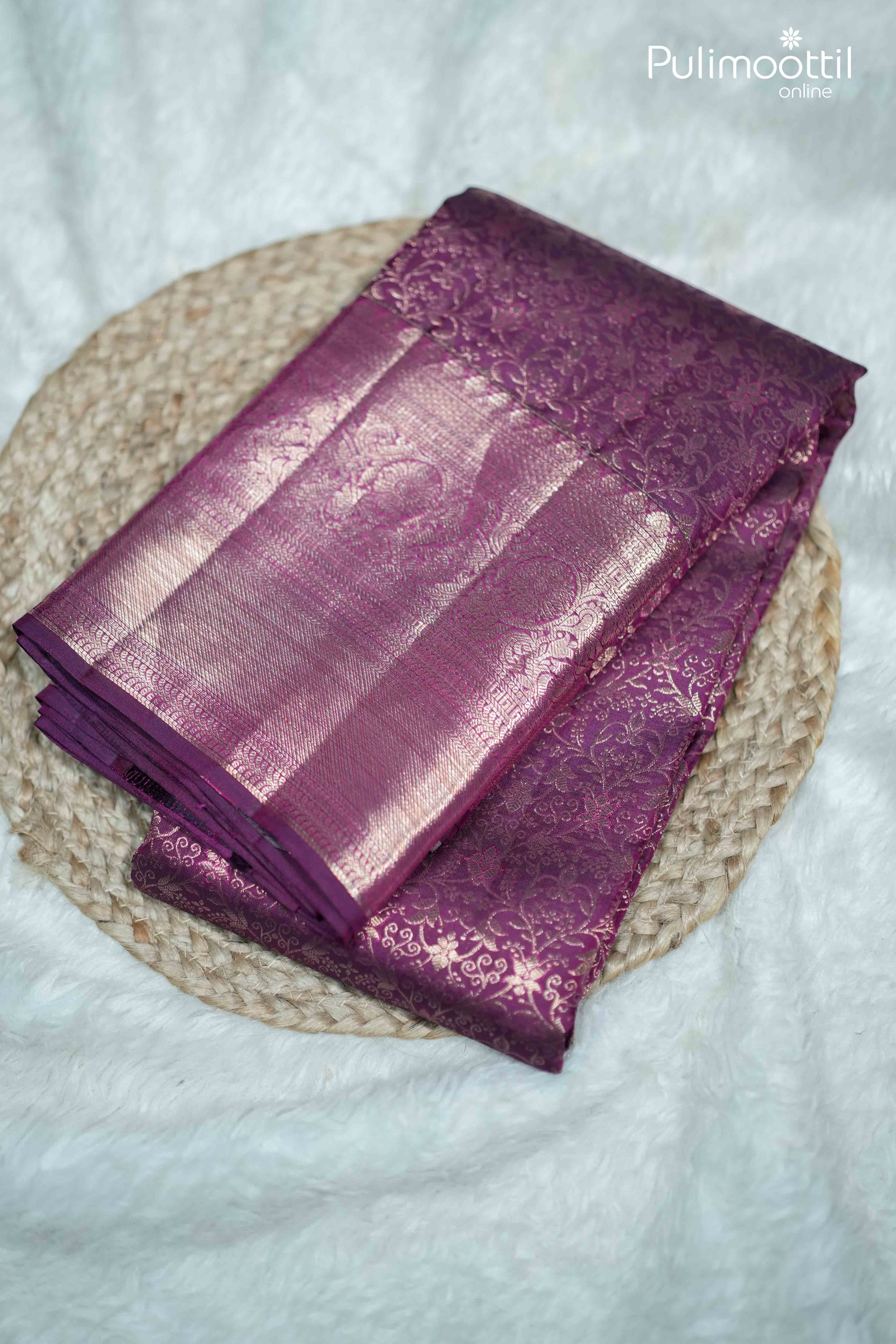 Folded purple plum Kanchipuram silk saree with intricate copper zari floral weaving, highlighting rich traditional craftsmanship and luxurious sheen, ideal for bridal and festive wear.
