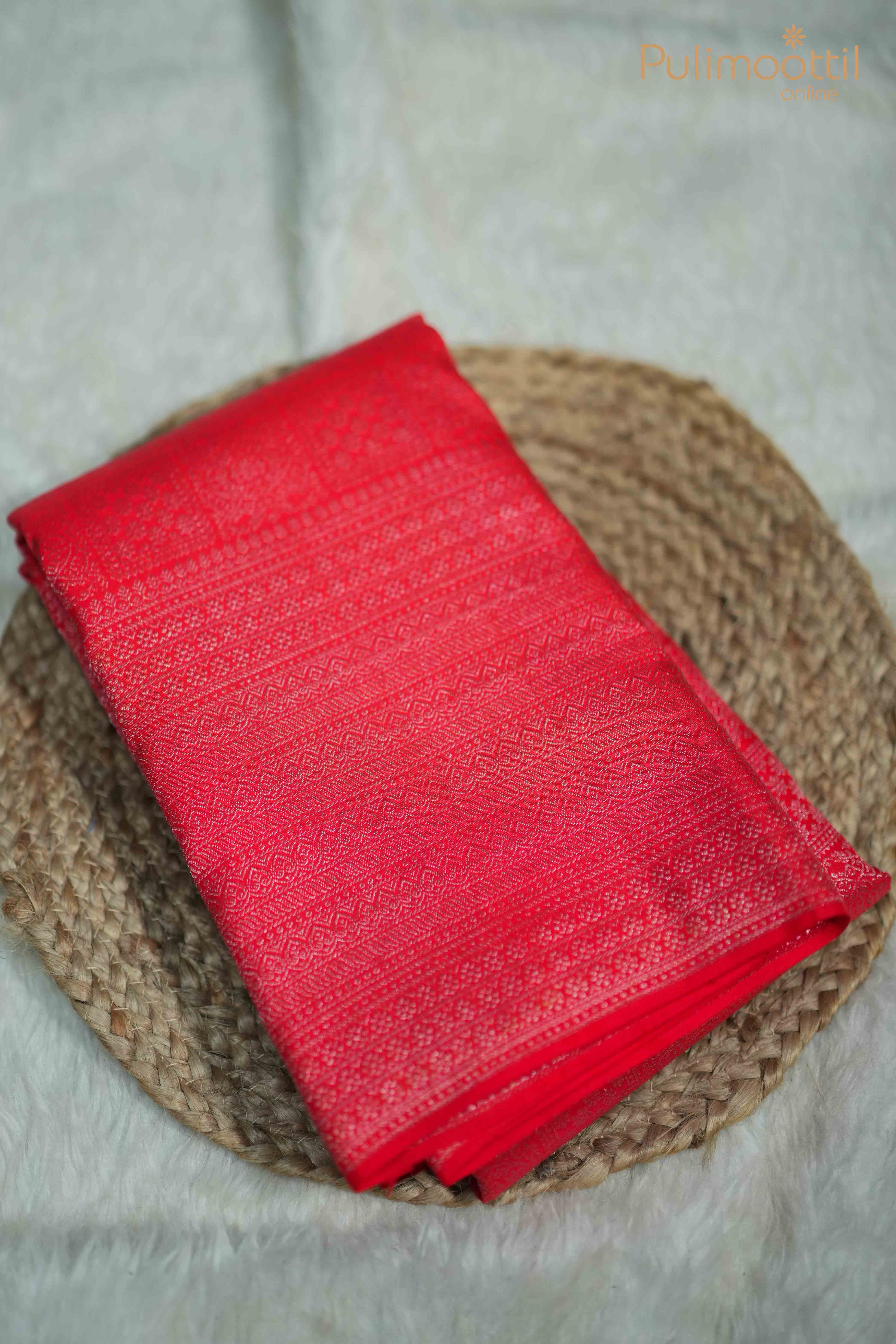 Folded Red Pure Kanchipuram fabric with silver zari square brocade design, showcasing its intricate texture and traditional elegance.