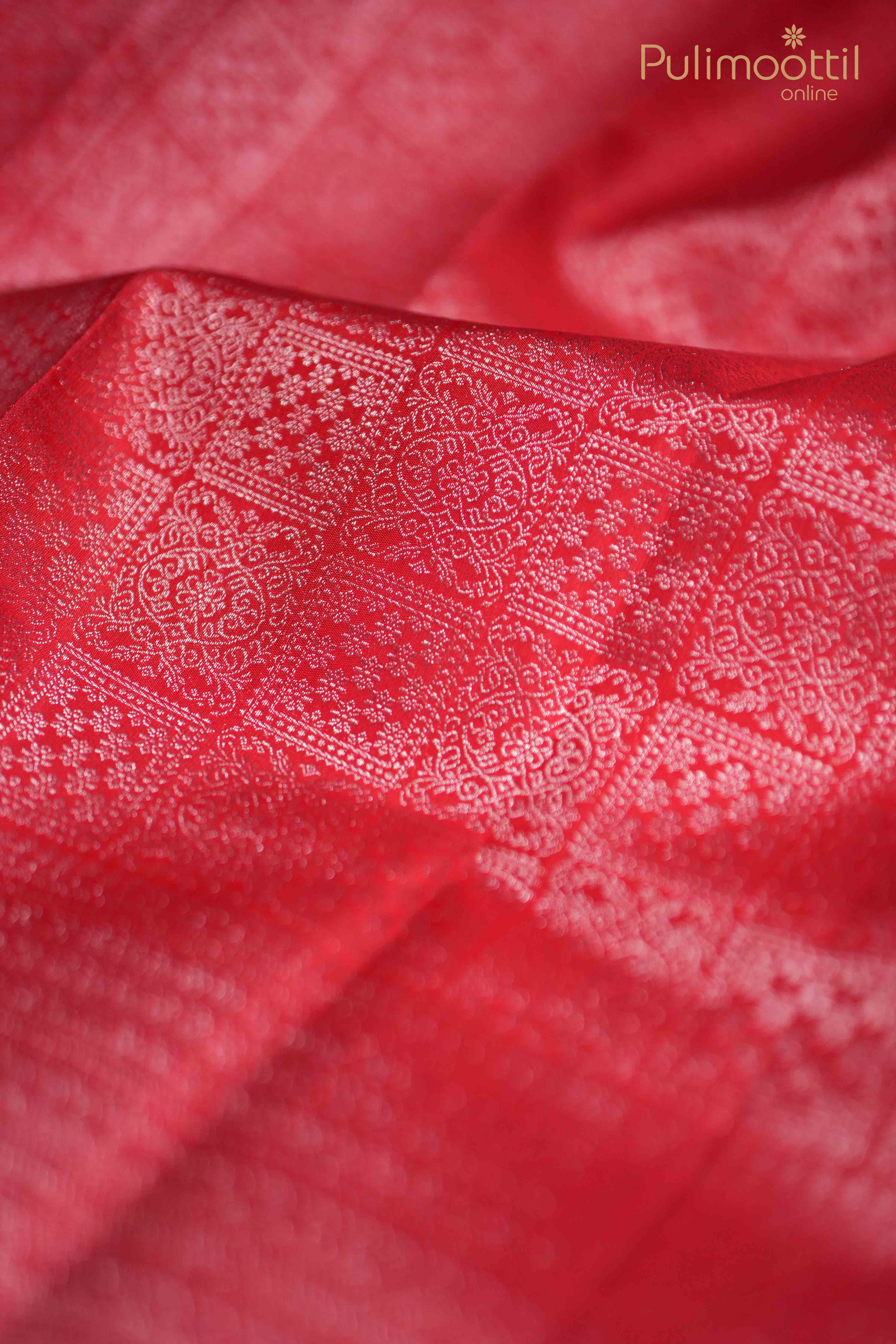 Close-up of Red Kanchipuram saree showcasing intricate silver zari square brocade design, highlighting the rich texture and traditional craftsmanship.