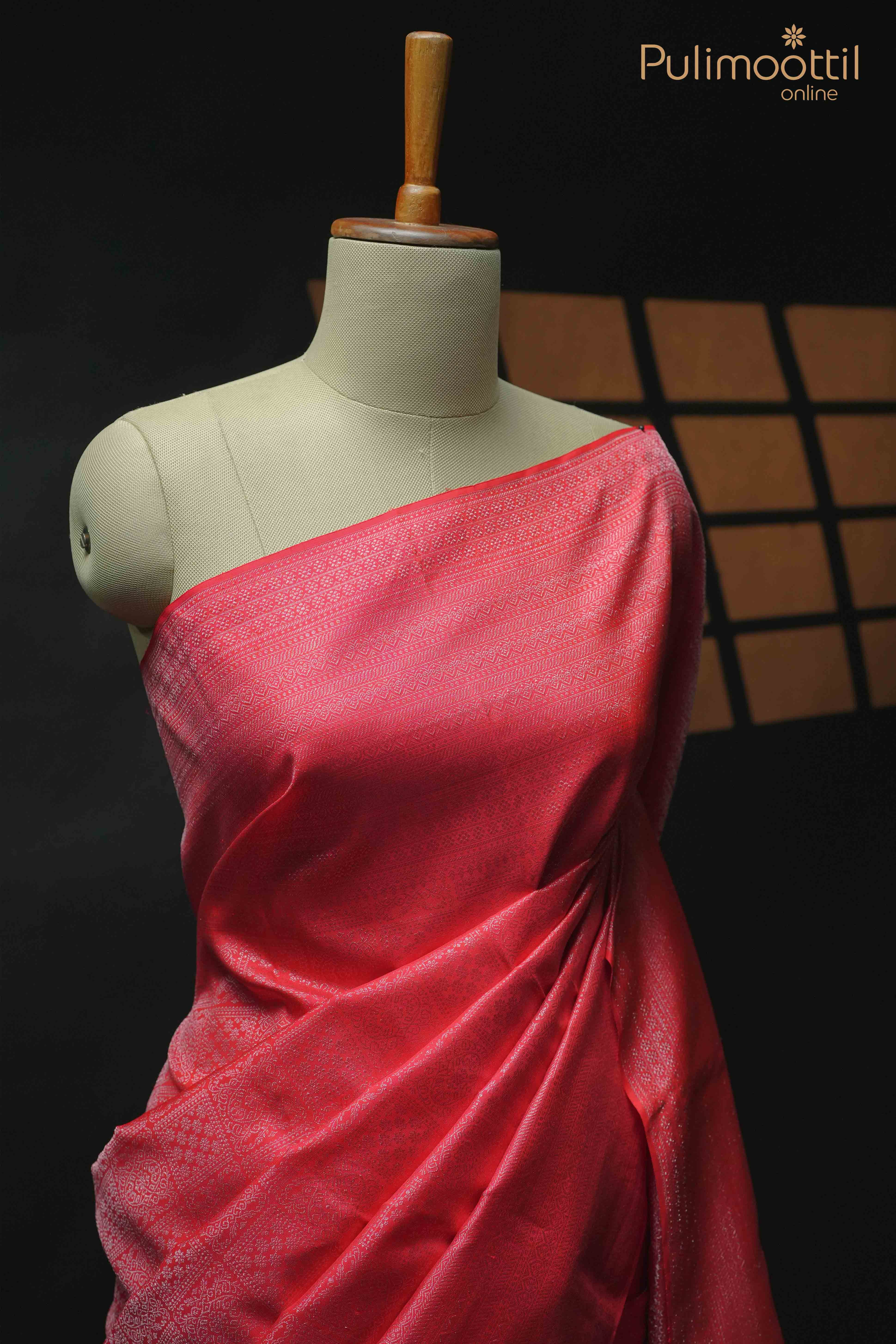 Red Kanchipuram wedding saree with silver zari square brocade and designer border, draped elegantly on a mannequin.