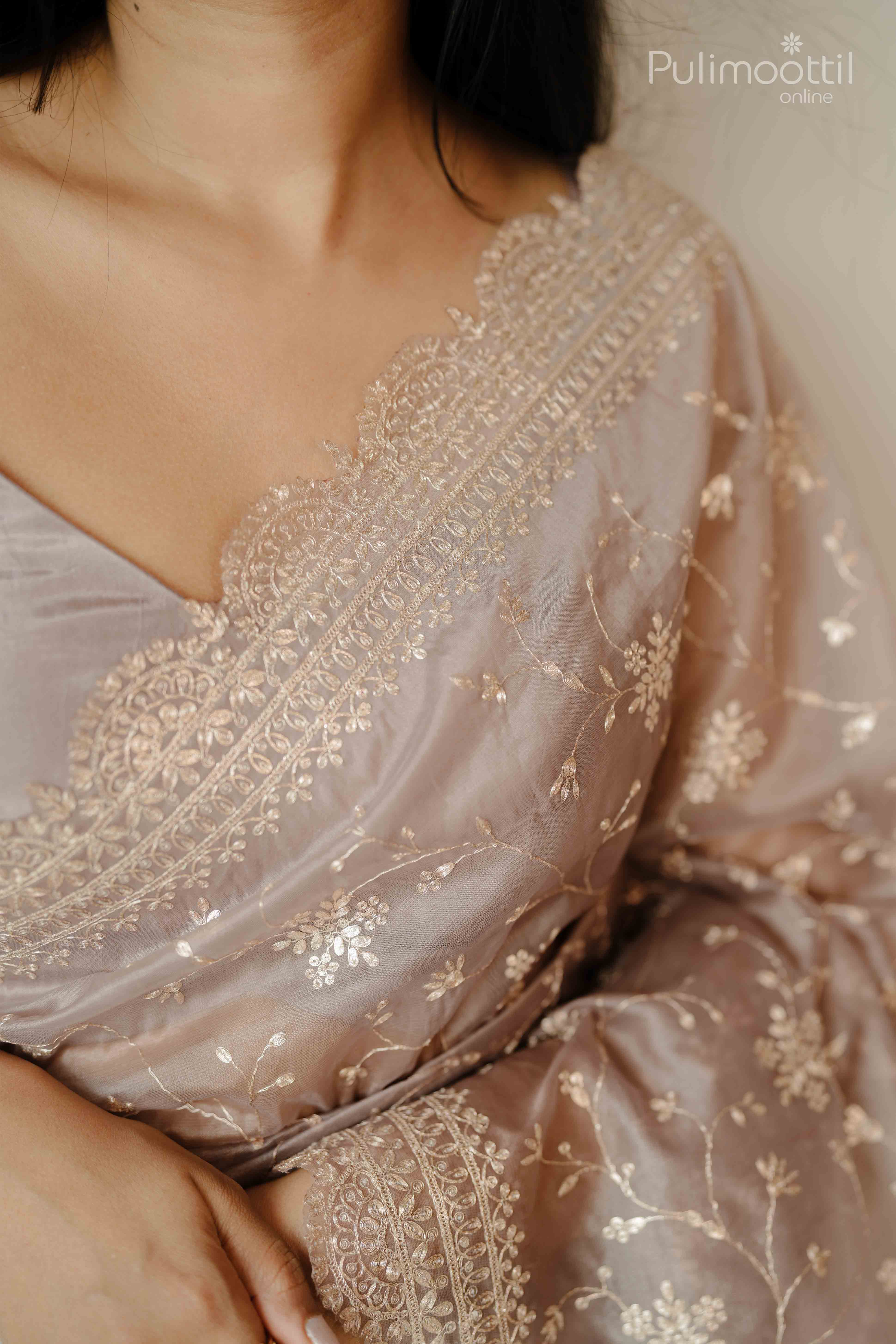 Detailed embroidery on scalloped border of rosy brown organza saree with pitta floral design – neckline close-up.