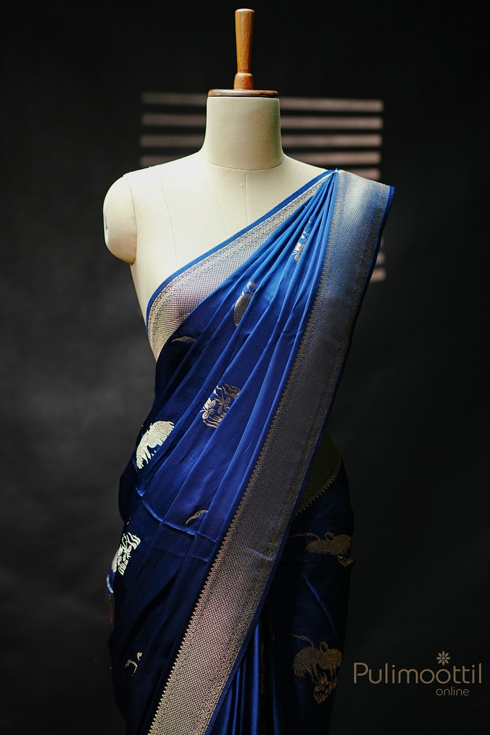 Royal blue Uppada silk saree with golden zari bird motif and geometric pattern zari border, draped elegantly on mannequin.
