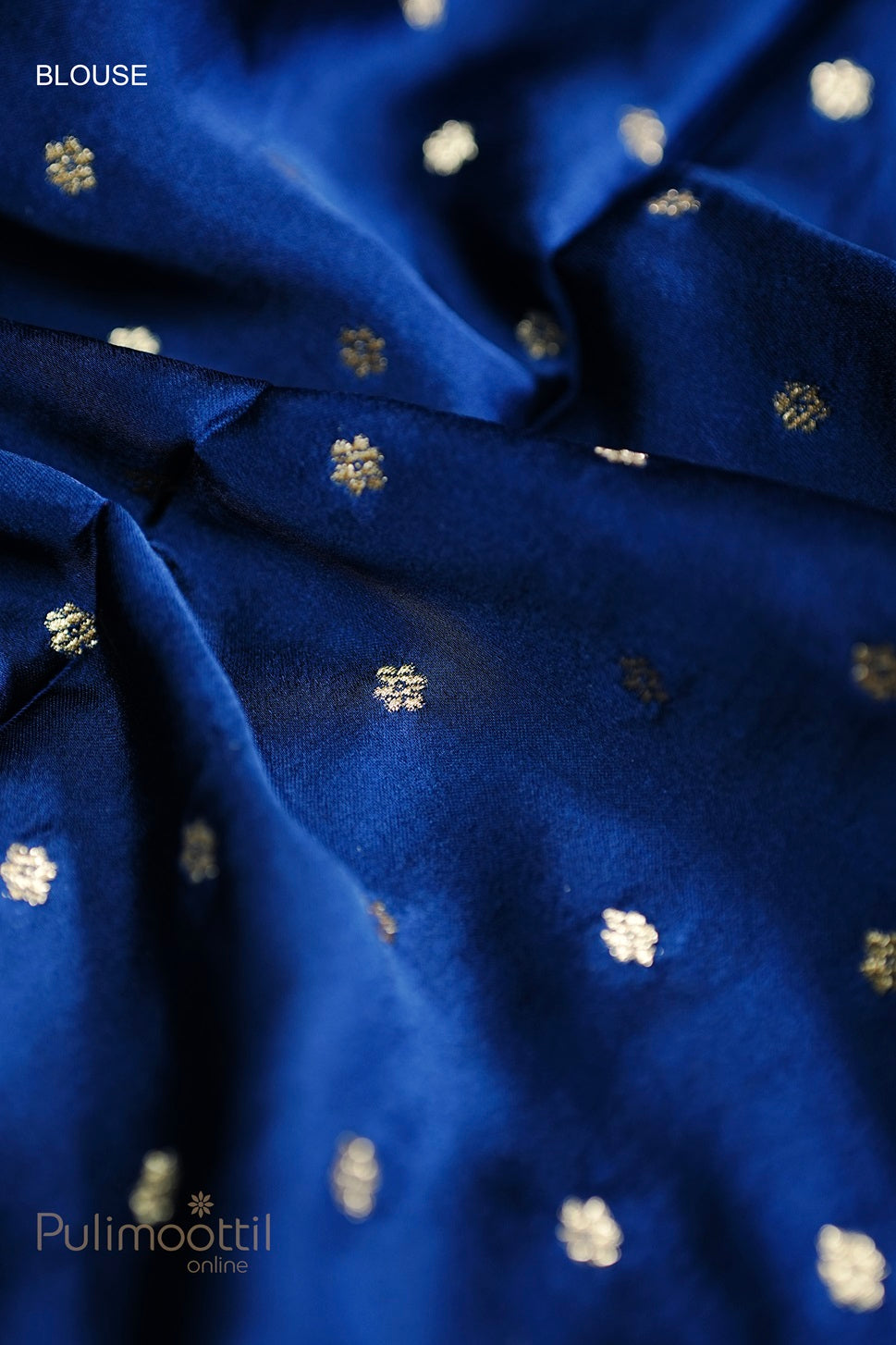 Close-up of royal blue Uppada silk blouse fabric with small golden zari floral motifs, showcasing its luxurious texture and detailed design.