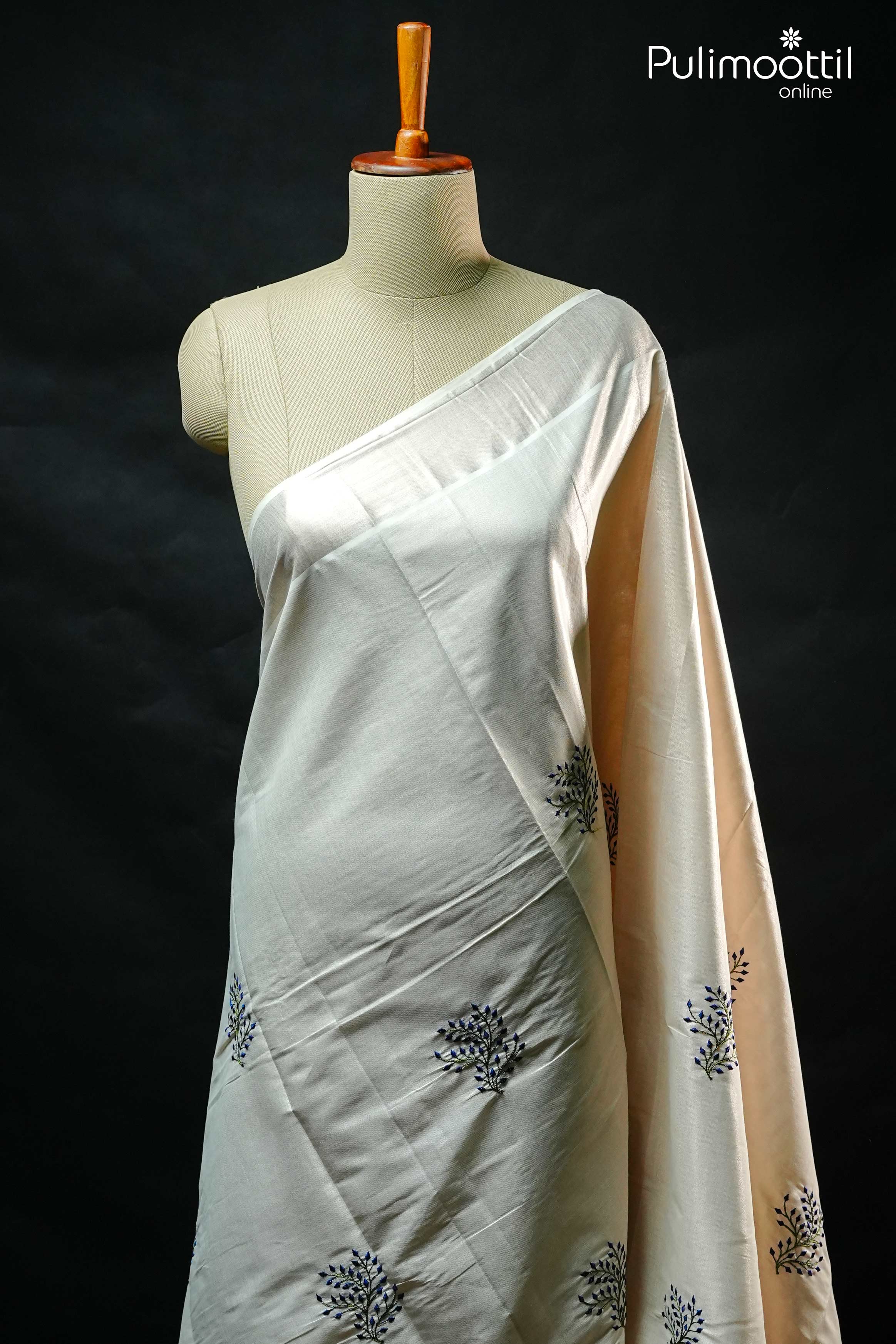Elegant silver Kerala tissue saree draped on mannequin showcasing thread work
