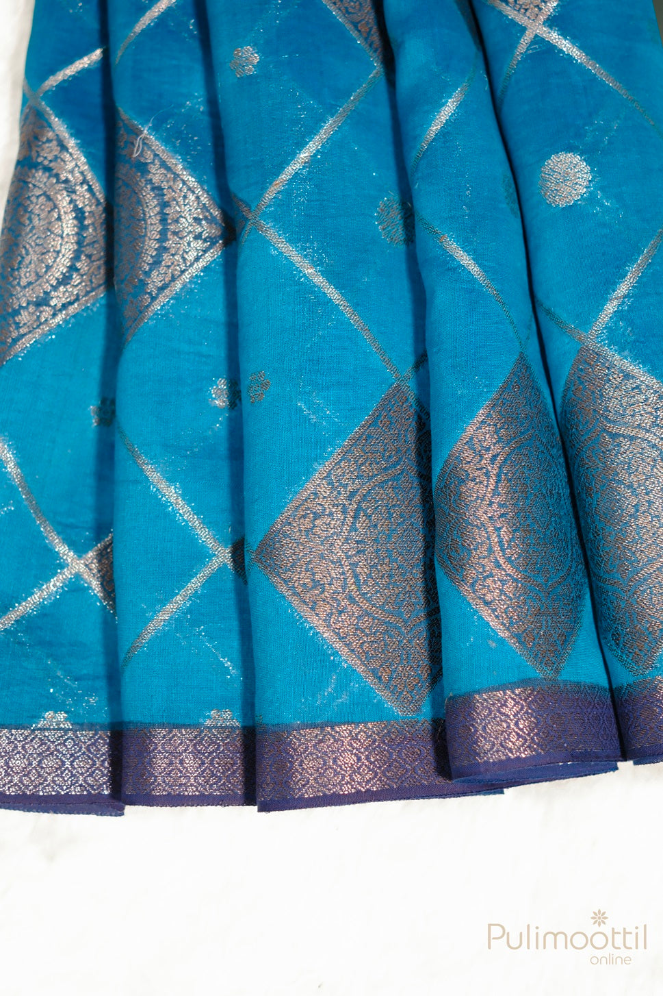 Close-up of the turquoise blue saree with silver zari square design and contrast border, capturing the rich texture and intricate detailing that make it an ideal choice for weddings and cultural events.
