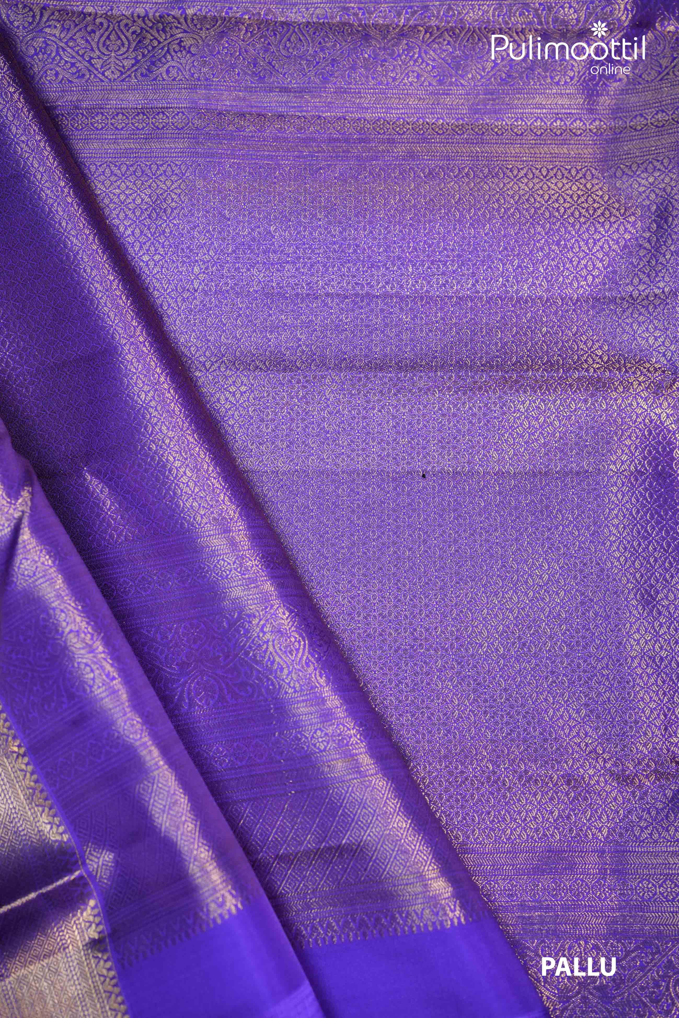 Close-up of the pallu of a violet Kanchipuram saree, featuring intricate golden zari floral and geometric designs, with a glossy texture and rich finish.