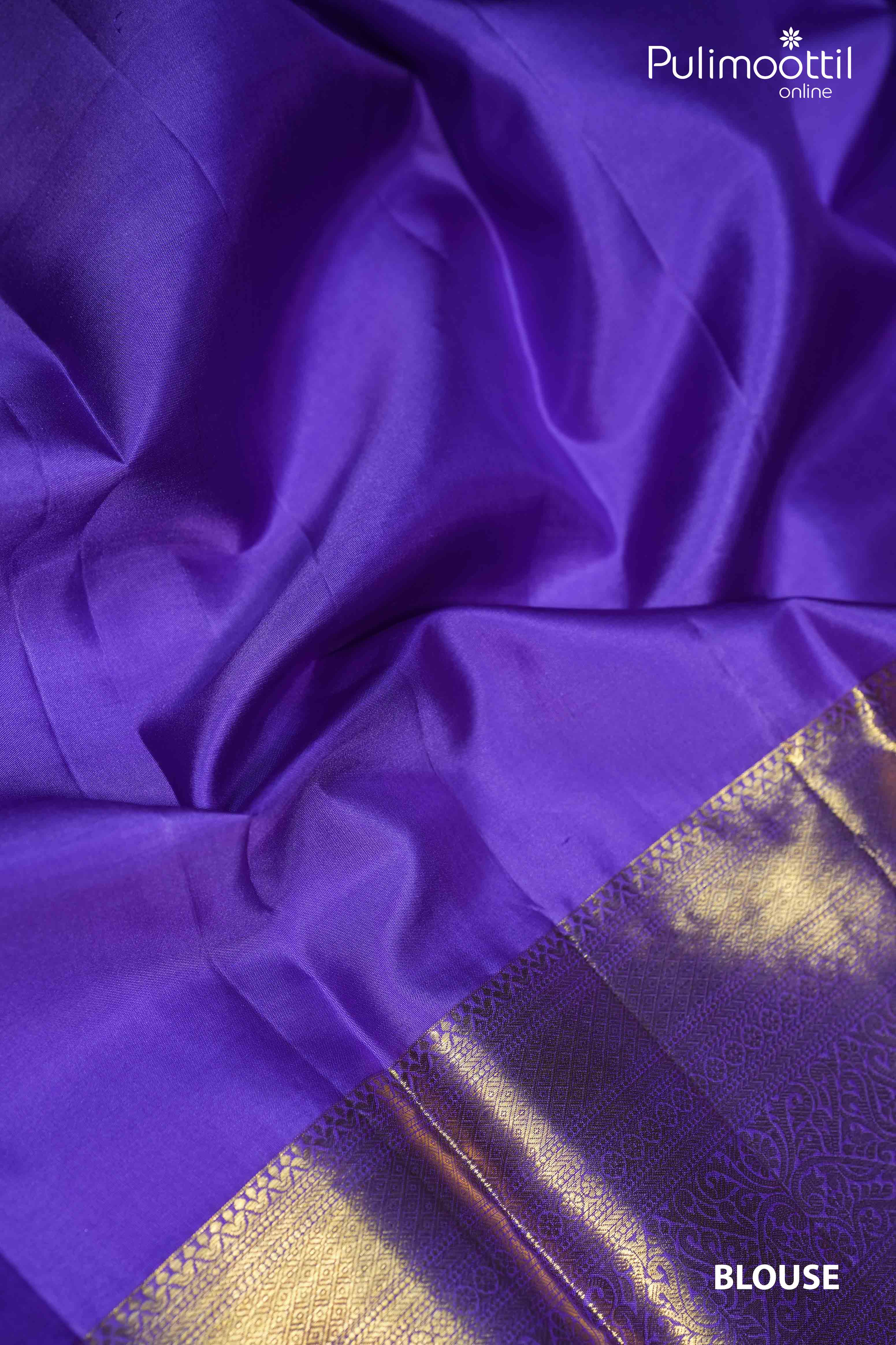 Close-up of a purple blouse piece from a Kanchipuram saree, with a golden zari border, highlighting the smooth fabric and intricate design.