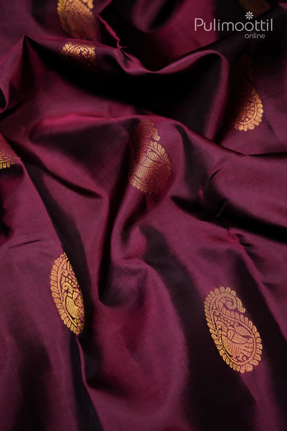 "Close-up view of the Wine Colour Pure Kanchipuram Silk Saree showcasing golden zari traditional mango motifs spread across the fabric, highlighting the rich, lustrous texture of the saree.