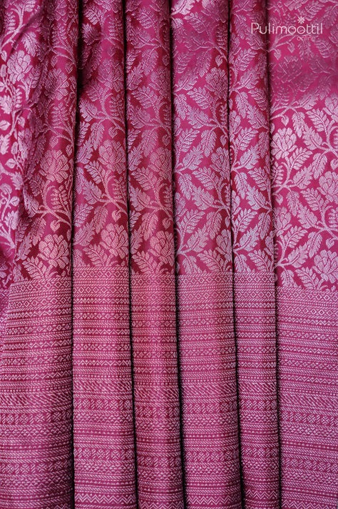 Folded pink silk saree with intricate floral patterns on the upper portion and geometric designs at the bottom, showcasing the rich texture and vibrant color, with the folds emphasizing the detailed craftsmanship of the fabric.