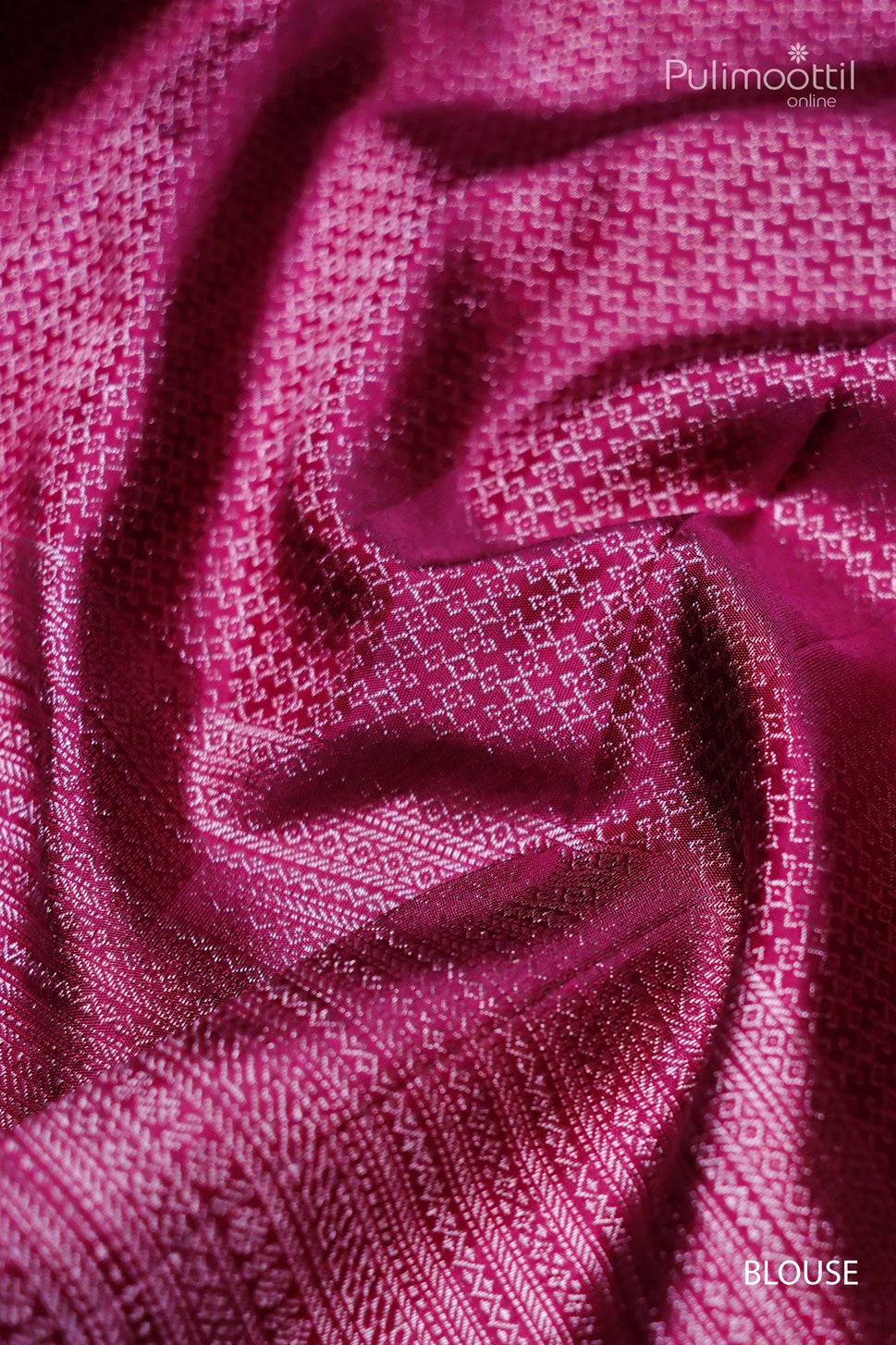 Close-up view of the pink fabric with geometric patterns, showcasing the glossy texture and intricate design details, ideal for a blouse. The fabric's folds highlight its luxurious sheen and fine craftsmanship.