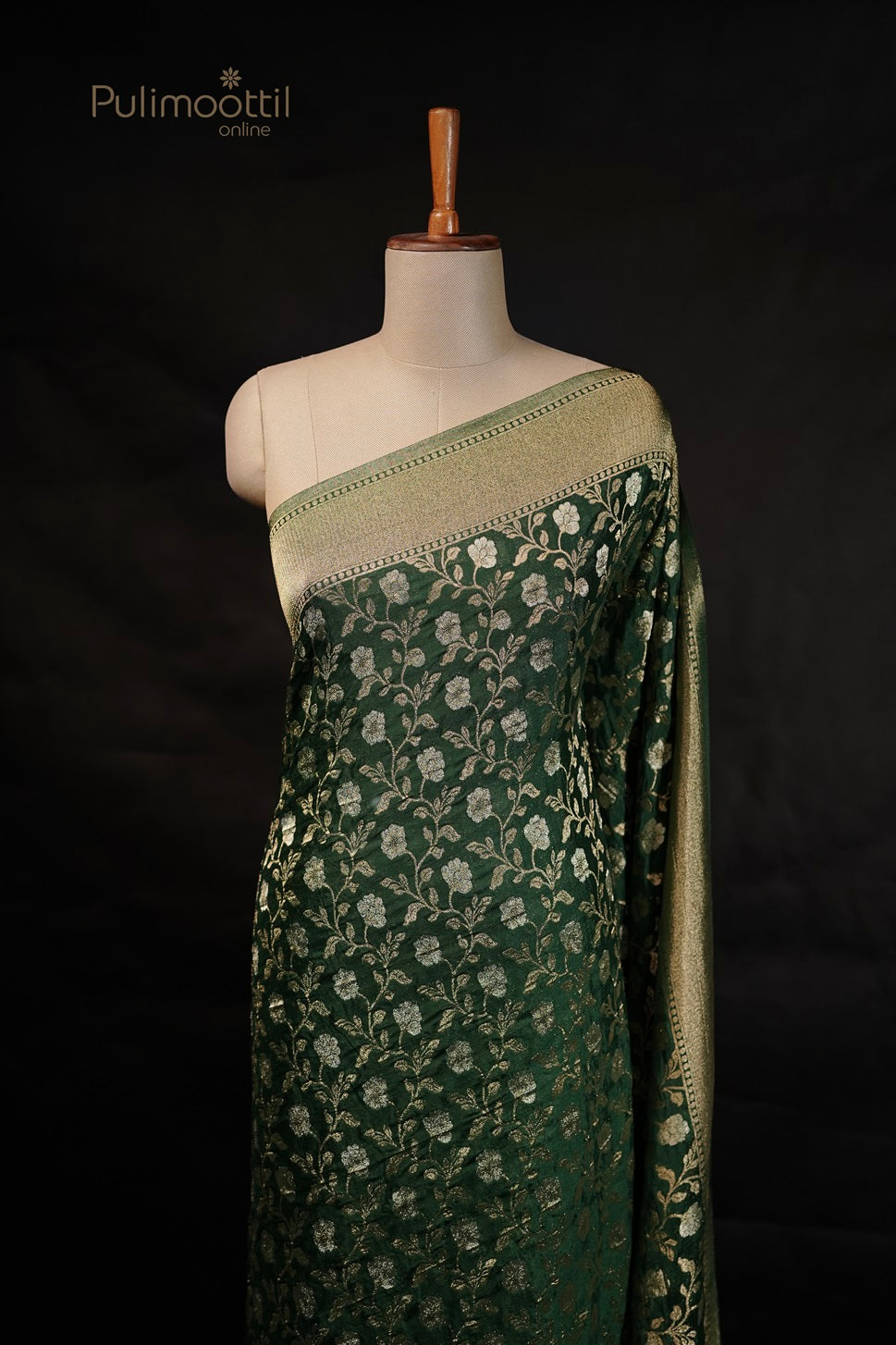 Bottle green Banarasi saree with golden and silver floral embroidery, displayed on a mannequin, featuring a contrasting golden border.
