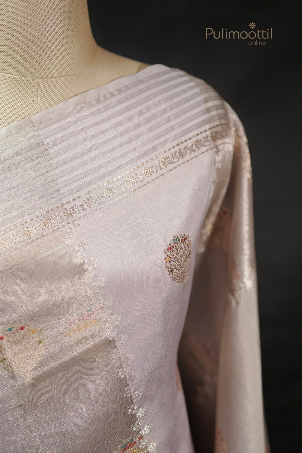 Close-up of ivory Banarasi silk saree on mannequin, showing golden and multithread motifs with red border, suitable for wedding saree or party wear.