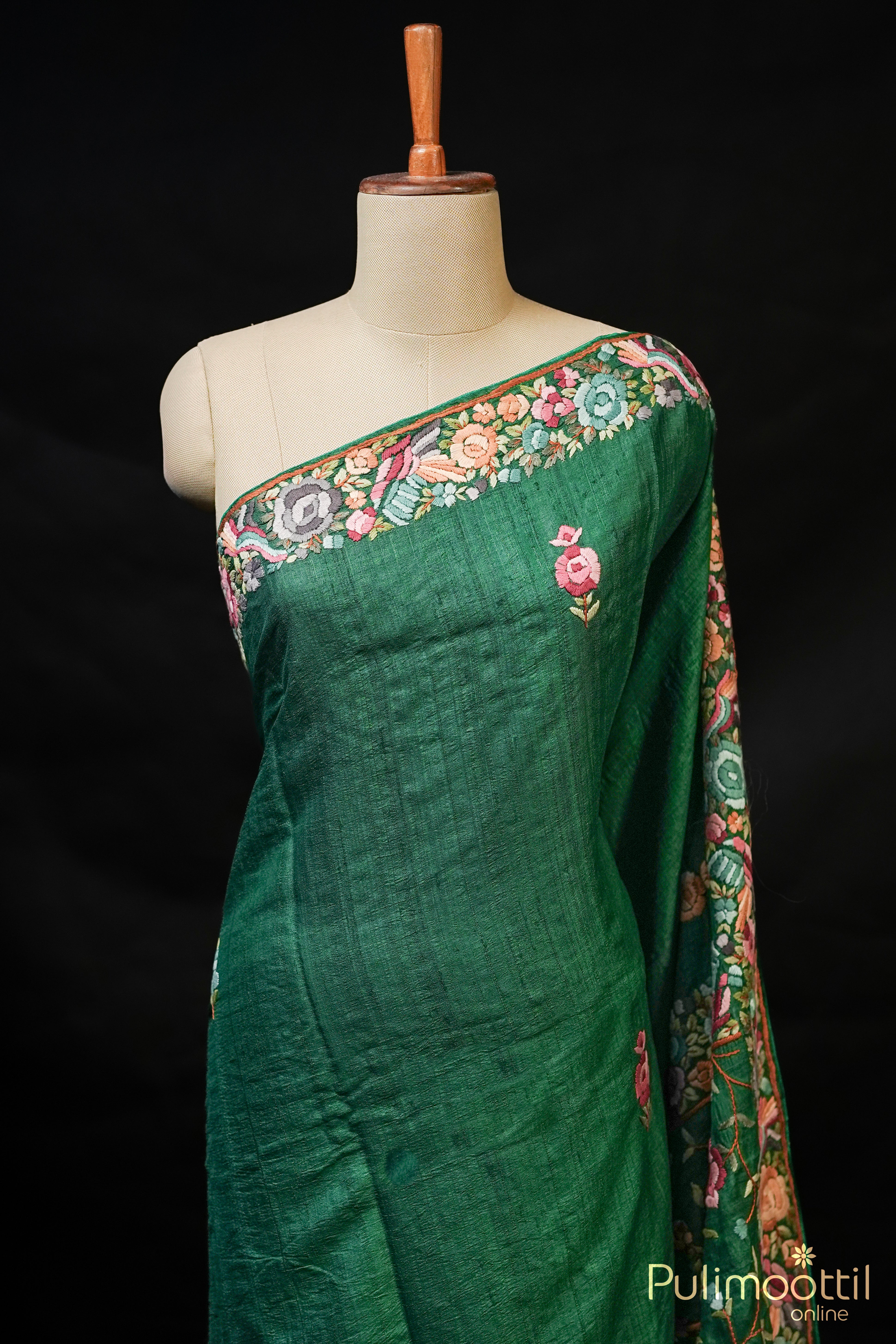 Bottle green hand embroidered jute silk saree with floral buttas and embroidered border.