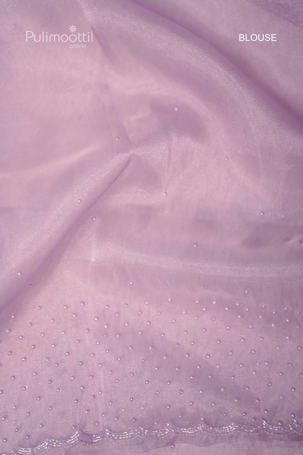 Lavender organza saree fabric with bead detailing and floral embroidery on the scallop border, paired with a spool of thread.