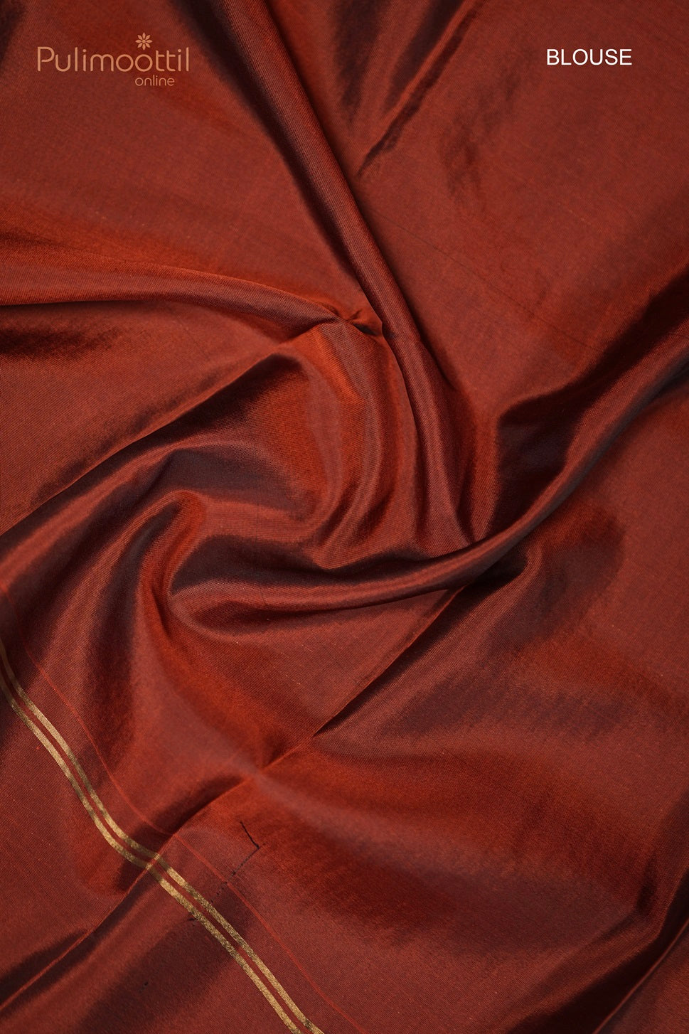Rust-colored plain blouse fabric with golden border detail, spread out on a flat surface.