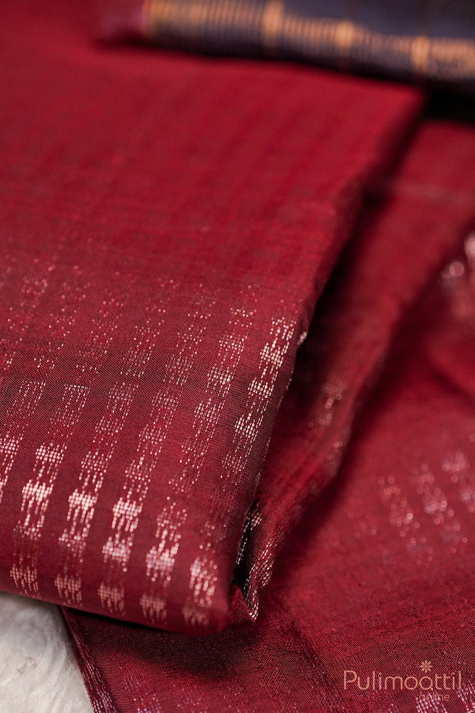 Close-up of maroon Kanchipuram saree fabric featuring rose gold zari work.