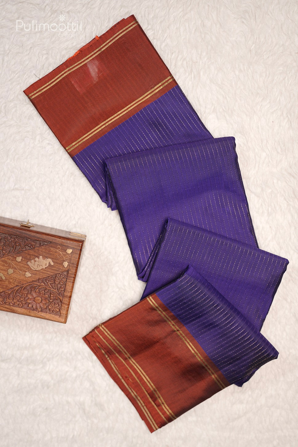 Close-up of violet saree fabric with golden stripes and rust-colored contrast border.
