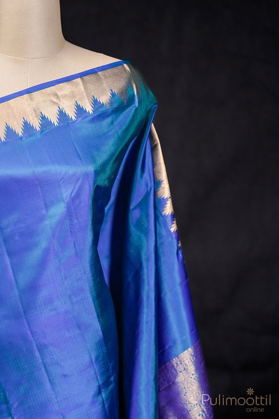 Close-up of peacock blue Kanchipuram saree draped on mannequin highlighting temple border.