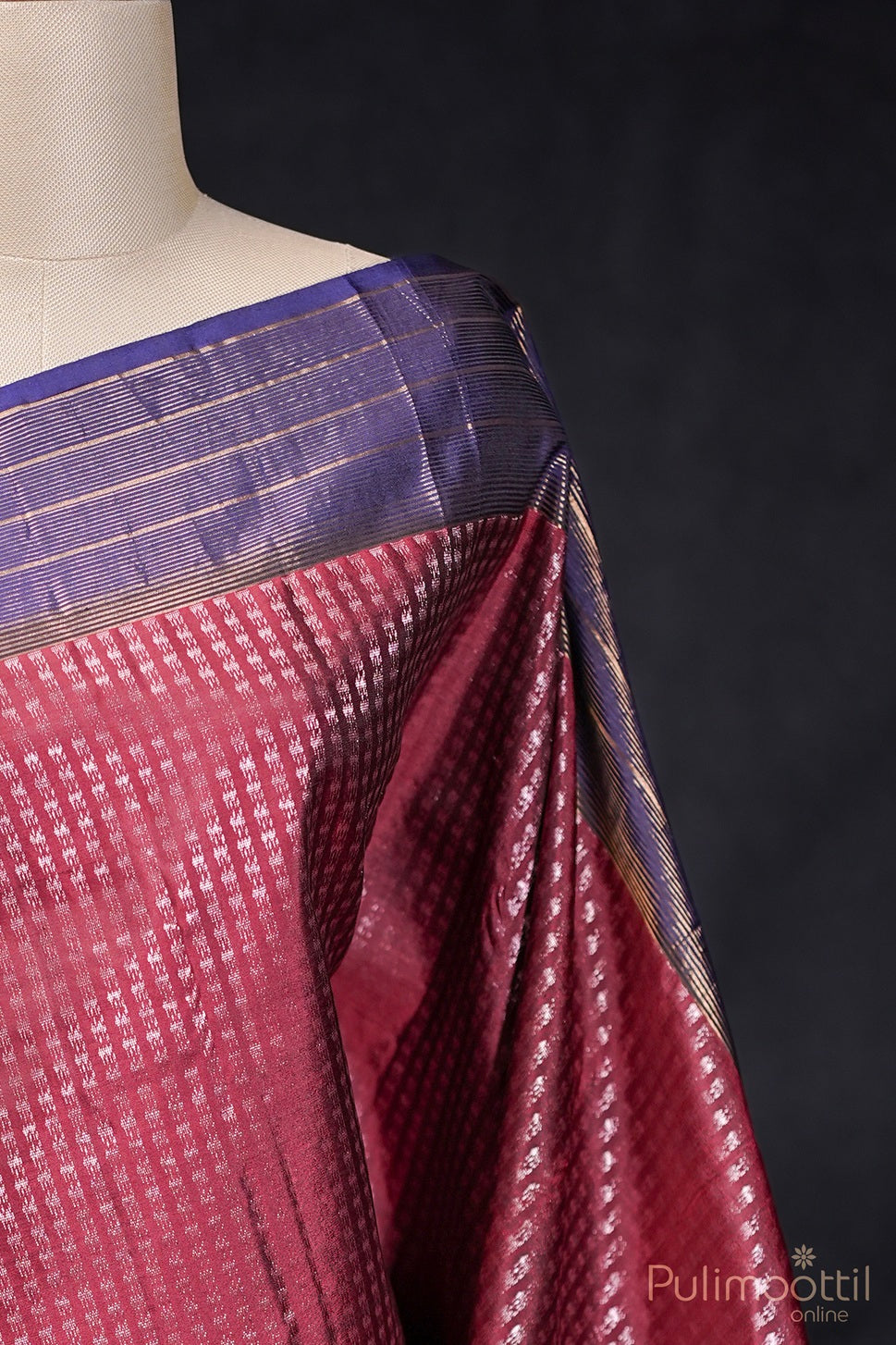 Detailed view of maroon Kanchipuram saree with rose gold zari and contrast blue border on mannequin.