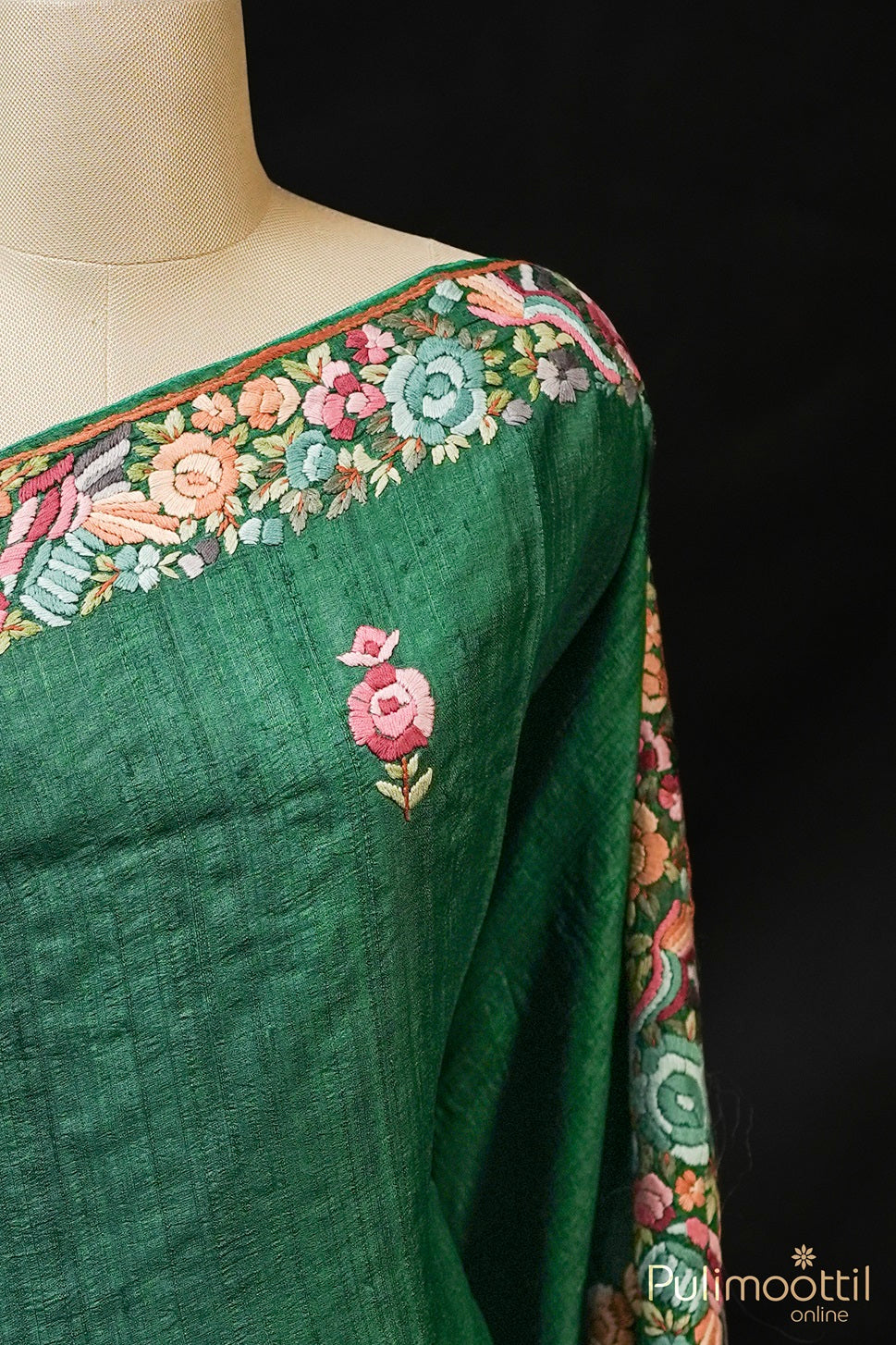 Close-up of bottle green jute silk saree showing hand embroidered border and butta.
