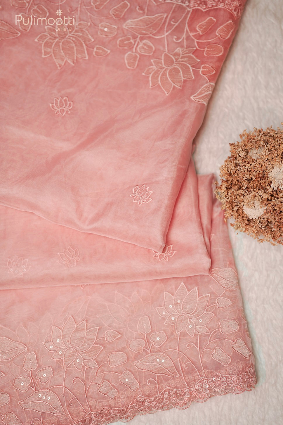 Detailed view of peach organza saree border with intricate lotus embroidery and scallop cut work, showcasing the wedding and bridal saree from Pulimoottil Silks Thrissu