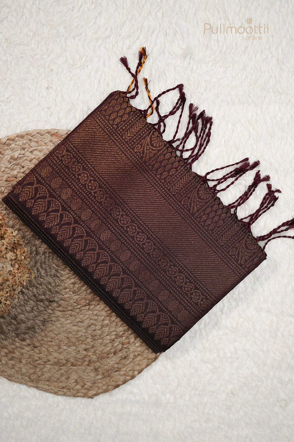 Top-down product image of the Dark Maroon Soft Silk Saree folded, clearly showing the densely woven designer pallu pattern with tassels.