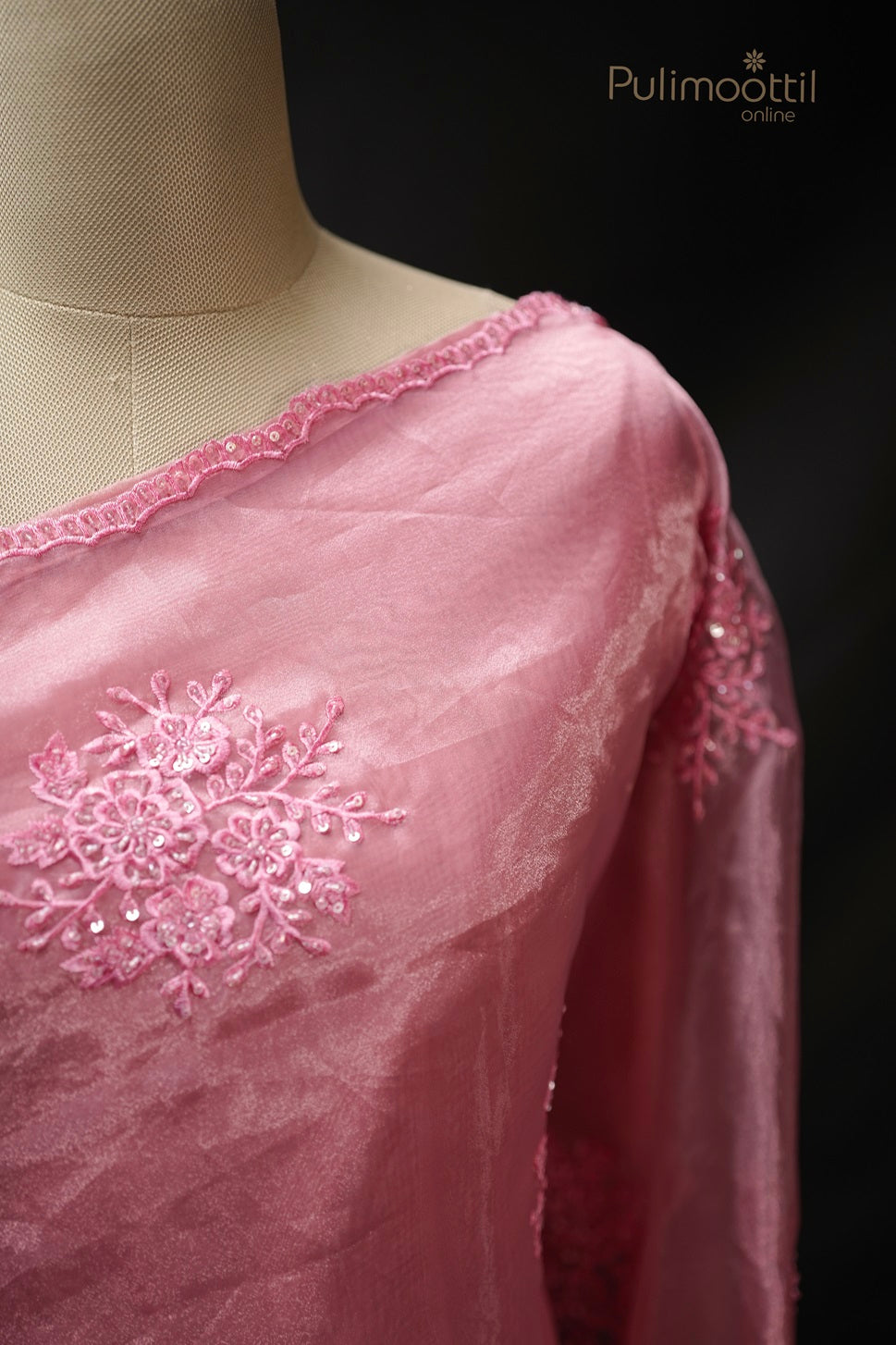 Detailed close-up of thread and sequins embroidery on light deep pink organza saree with scallop border, showcasing fine craftsmanship for wedding and bridal sarees by Pulimoottil Silks.