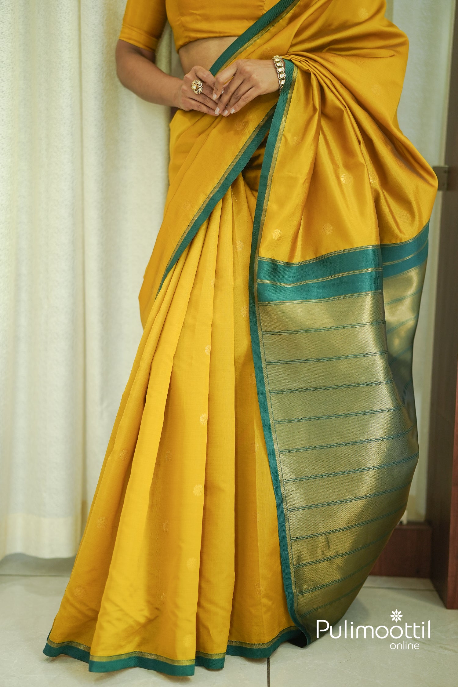 Detailed shot of the saree's hem and pallu, showcasing the rich Golden Tissue weave with horizontal Teal Green stripes