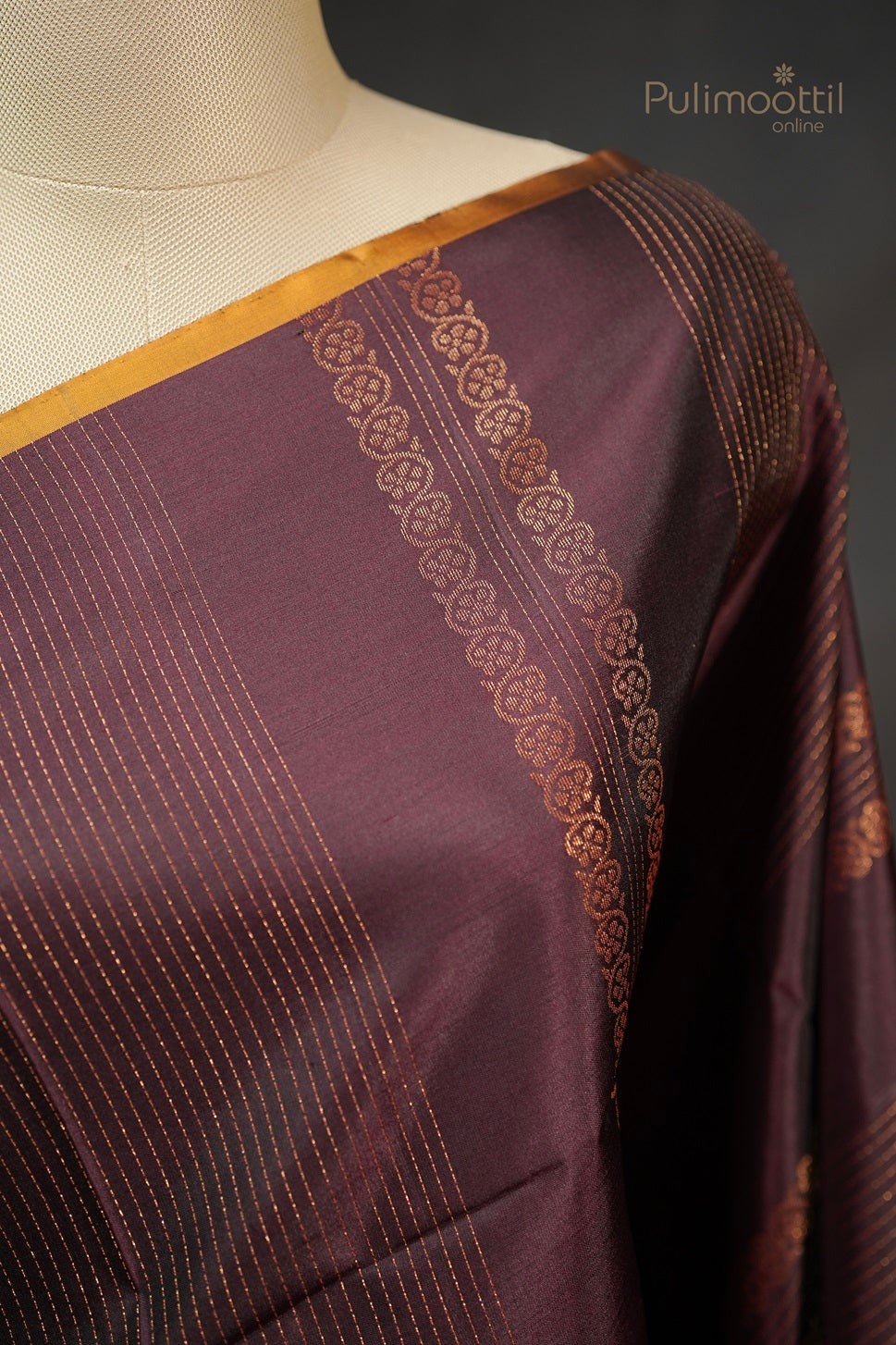 Close-up of the Dark Maroon Saree on a mannequin shoulder, highlighting the golden designer stripes and floral motif contrast border