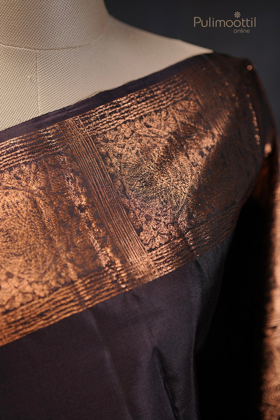 Close-up view of the gold zari border on the black Kanchipuram soft silk saree displayed on a mannequin.